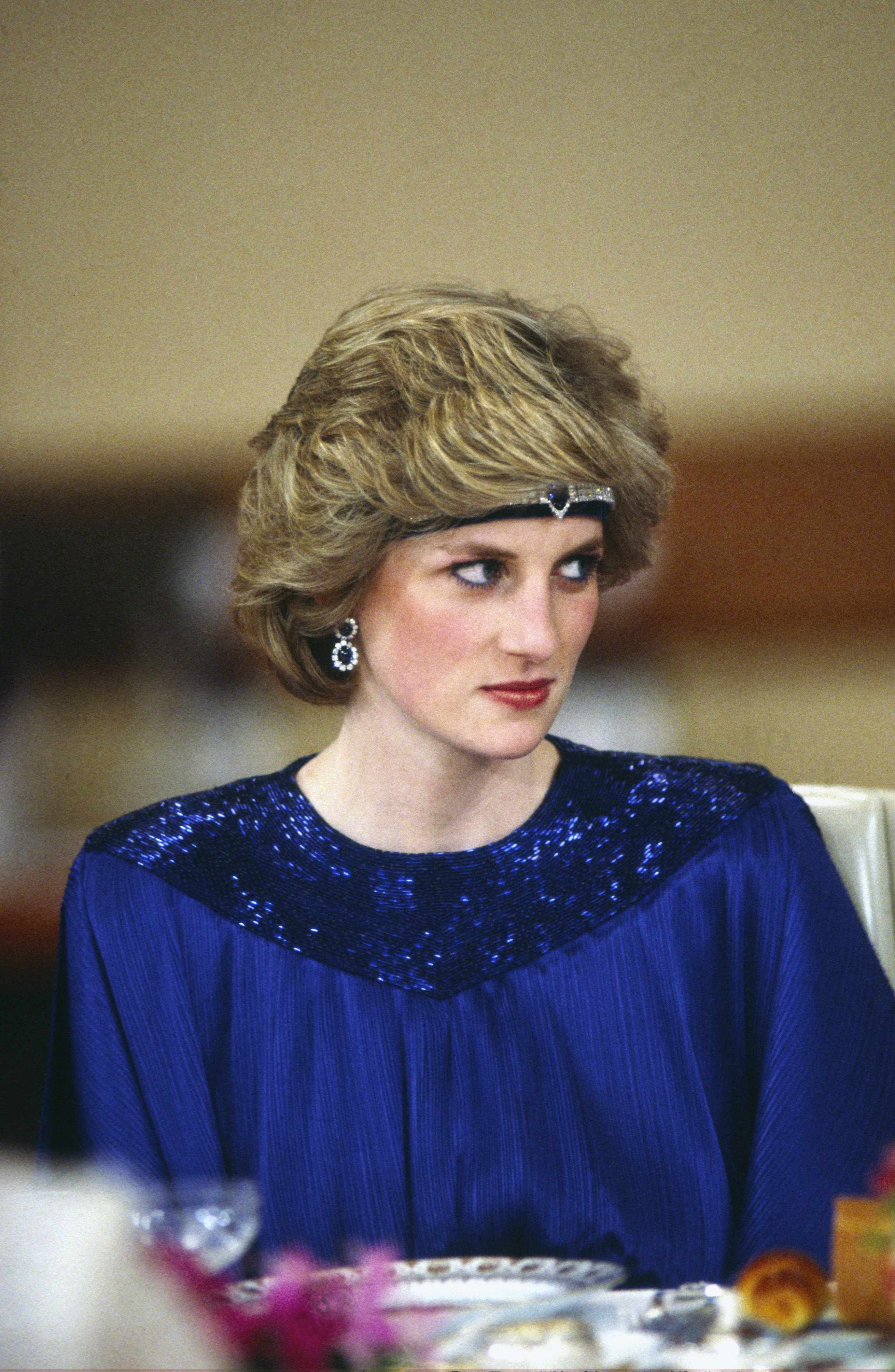 Diana, Princess of Wales at a dinner hosted by Emperor Hirohito in Japan, She is wearing a pleated royal blue evening dress designed by fashion designer Yuki and a sapphire and diamond headband made from jewels which she had reset from the Saudi suite converting the watch into a choker to wear on her forehead on May 12, 1986. | Source: Getty Images