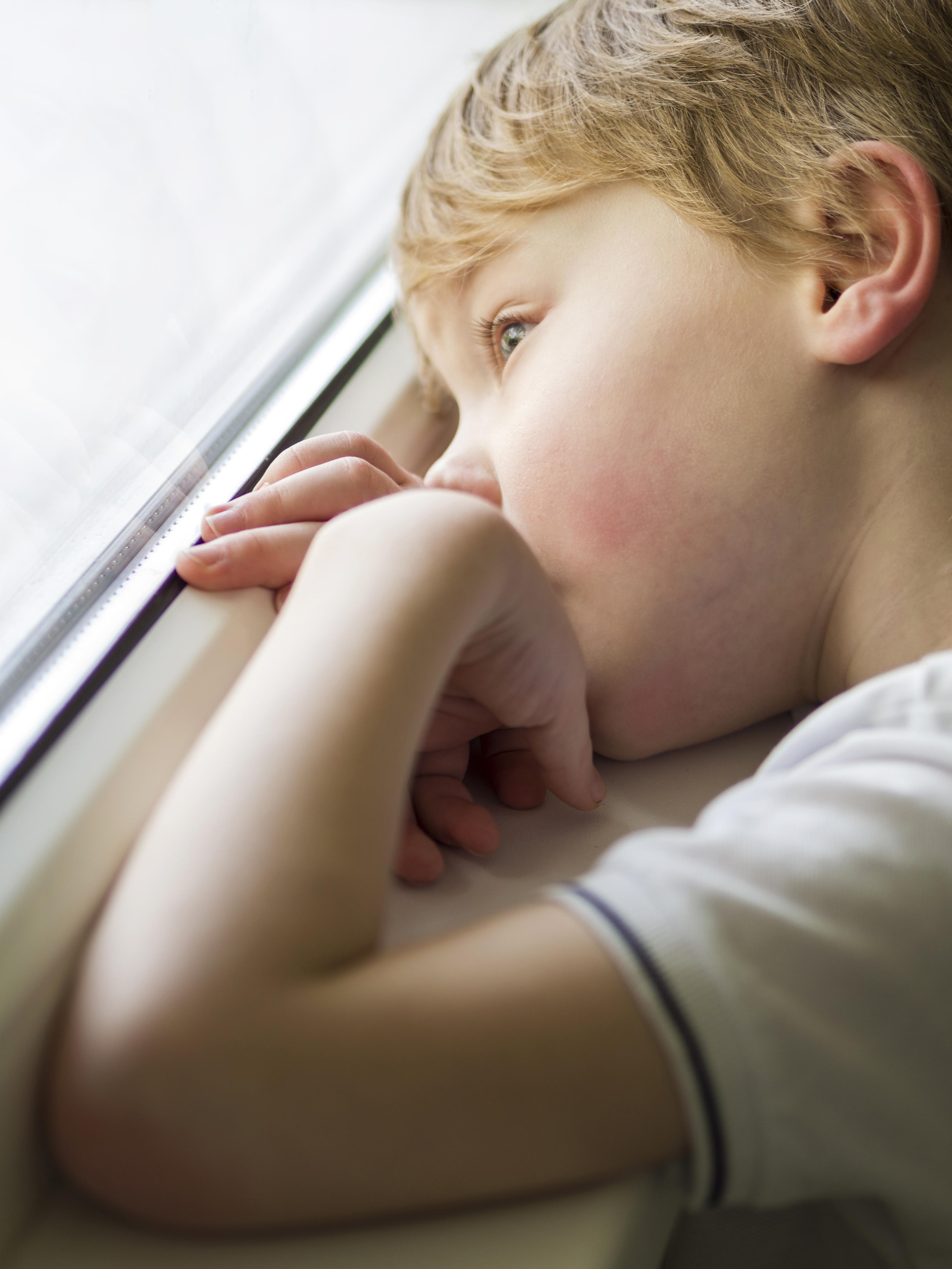 A sad little boy looking out the window | Source: Freepik