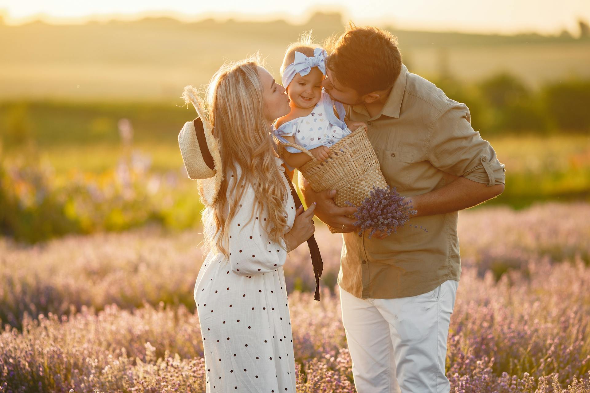 A couple kissing their baby daughter in a lavender field | Source: Pexels