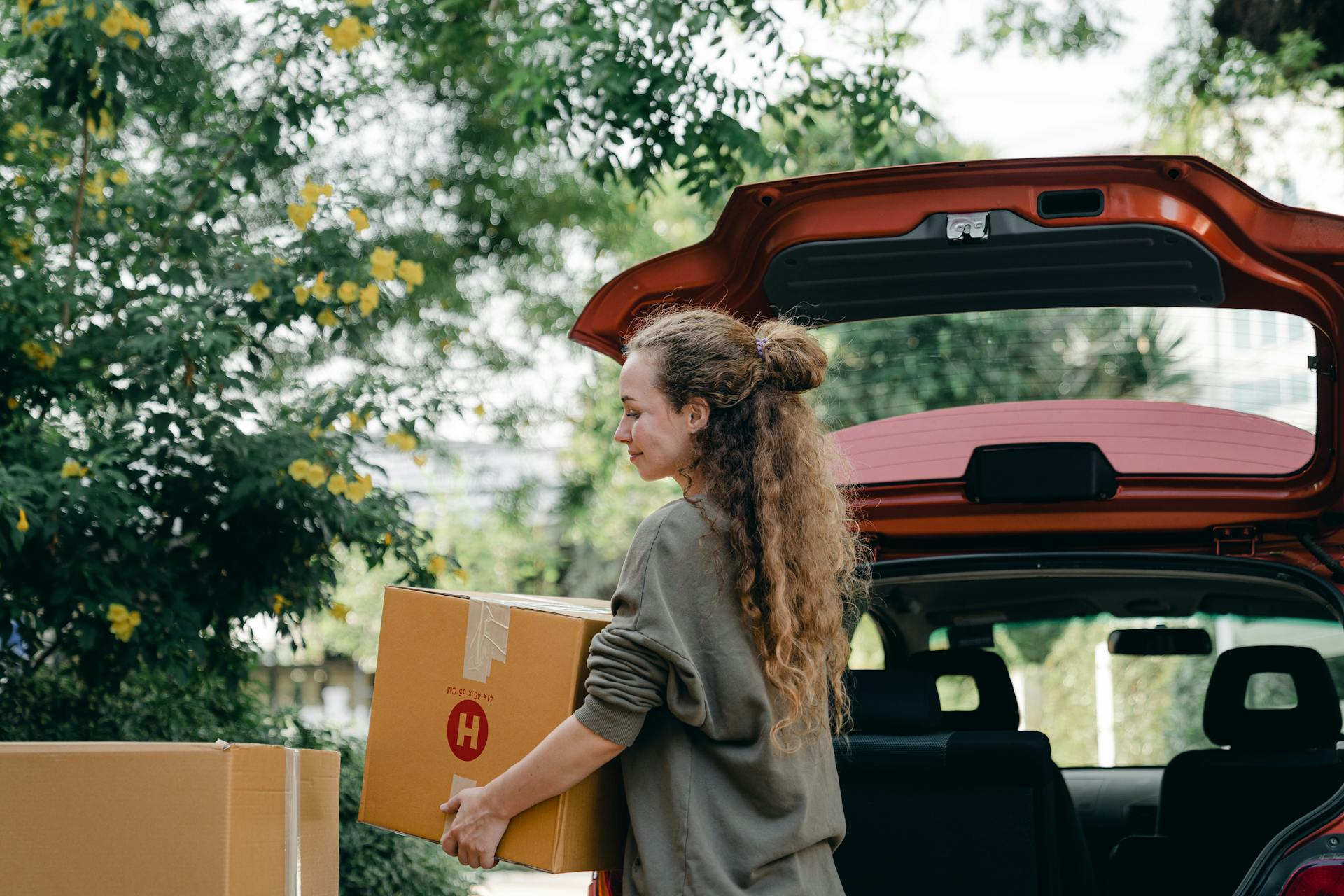 A woman loading cardboard boxes into her car | Source: Pexels
