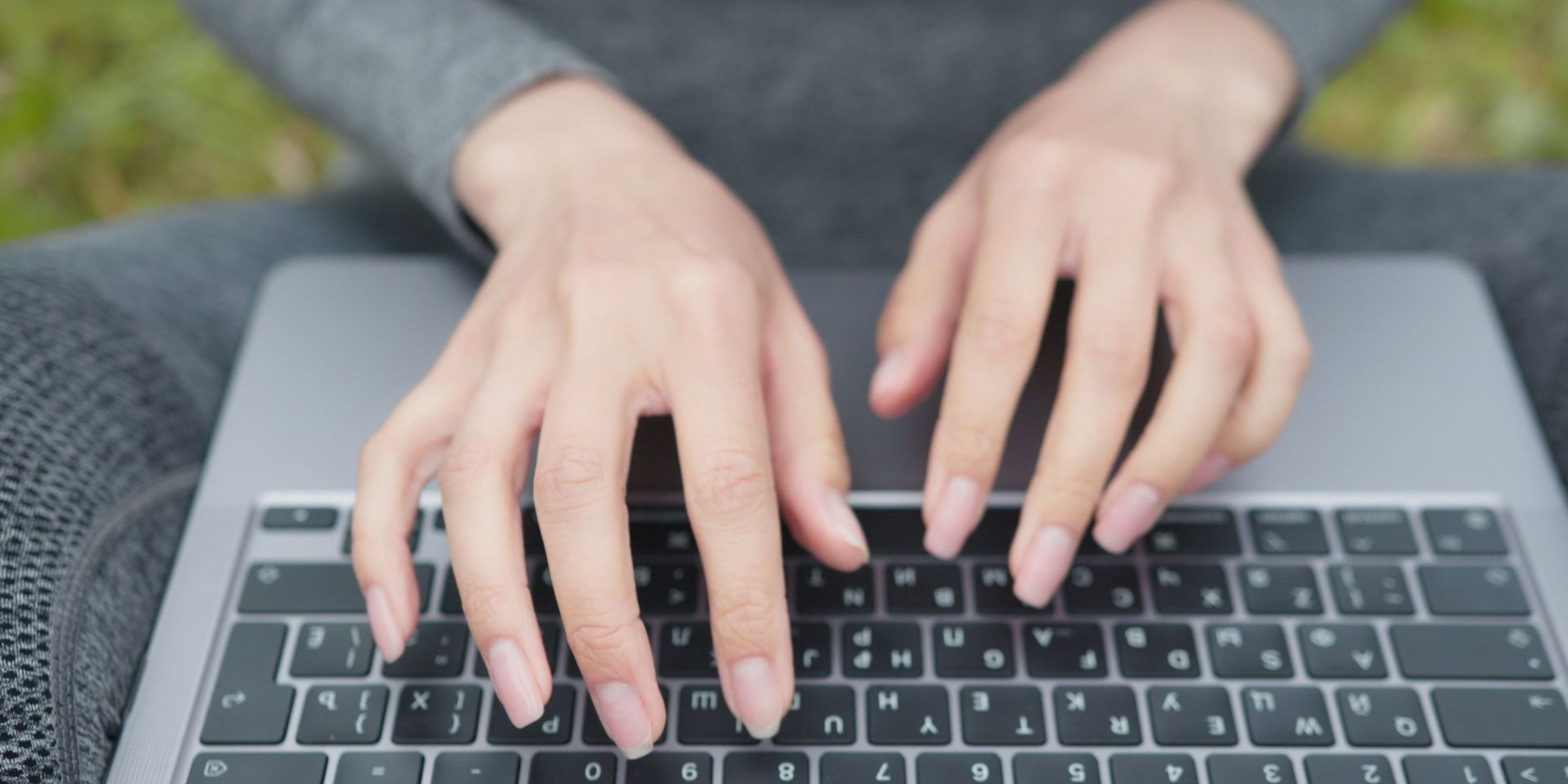 Person typing on a laptop keyboard outdoors | Source: Pexels