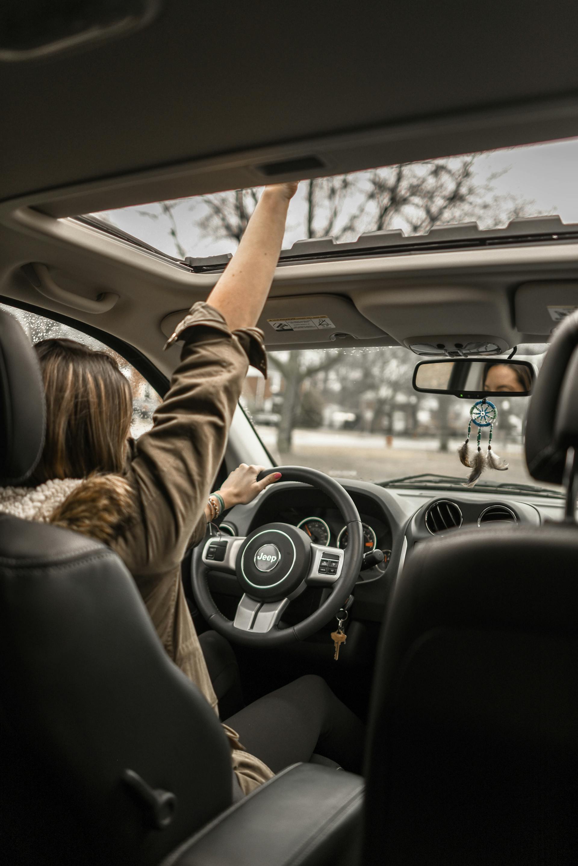 A woman waving through an open sunroof in a car | Source: Pexels
