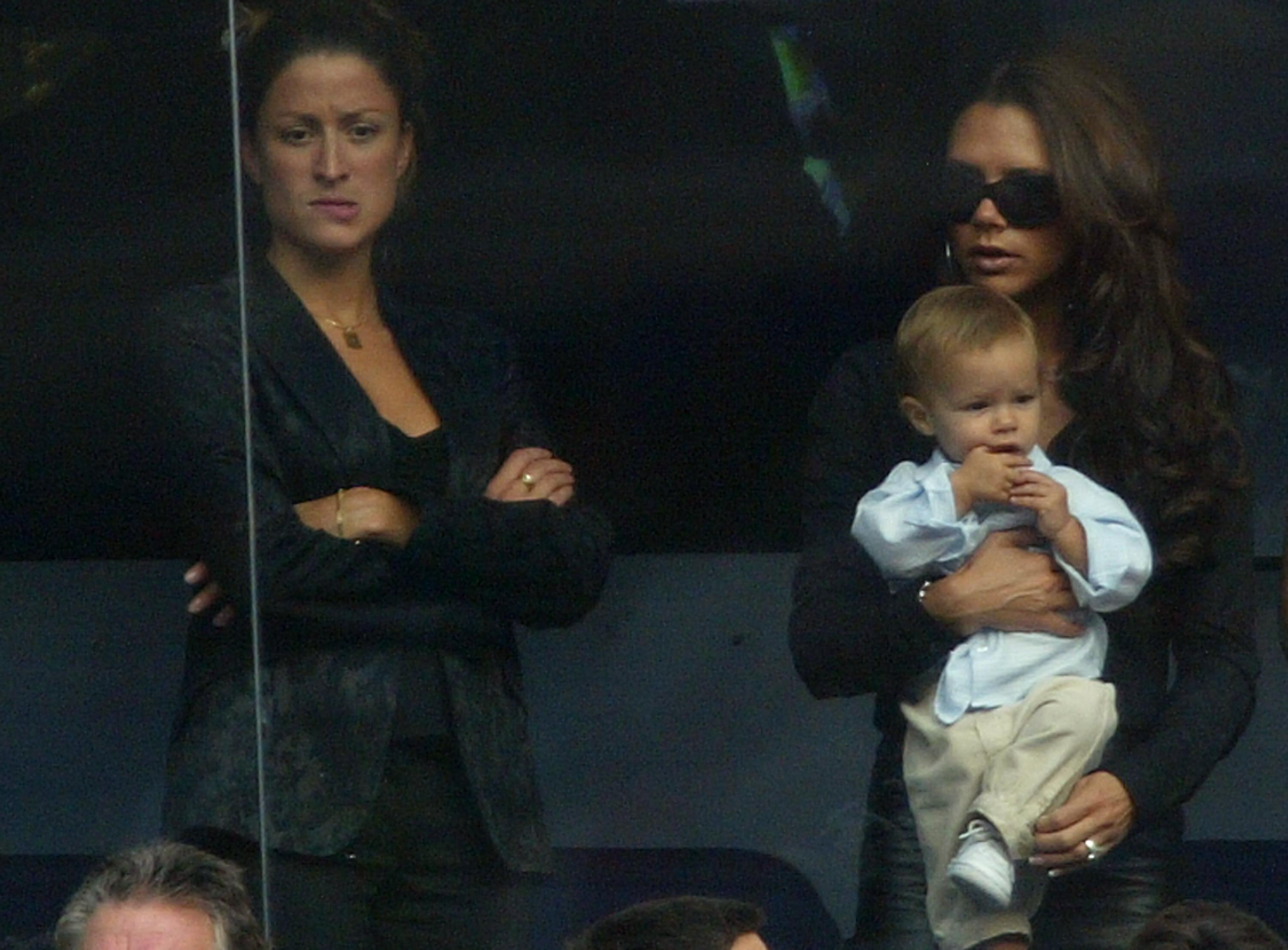 Victoria Beckham holds son Romeo beside David Beckham's PA Rebecca Loos during the Spanish Primera Liga match between Real Madrid and Valladolid at the Santiago Bernabeu Stadium on September 13, 2003, in Madrid, Spain. | Source: Getty Images