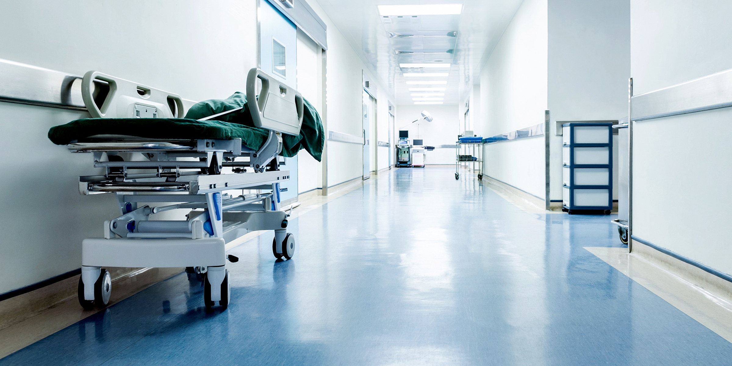 An empty hospital hallway with a stretcher parked along the wall | Source: Shutterstock
