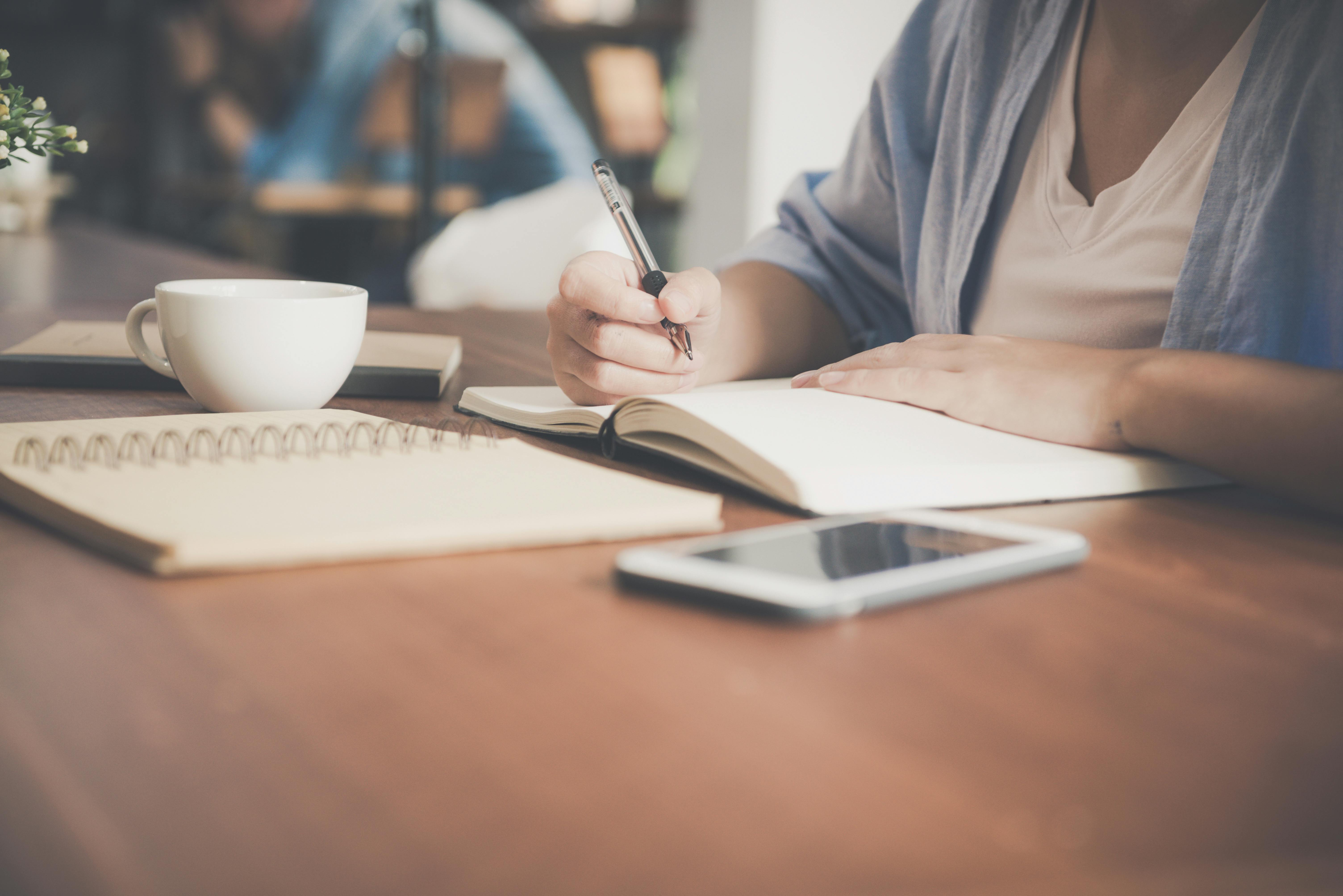 A person writing on a note book | Source: Pexels