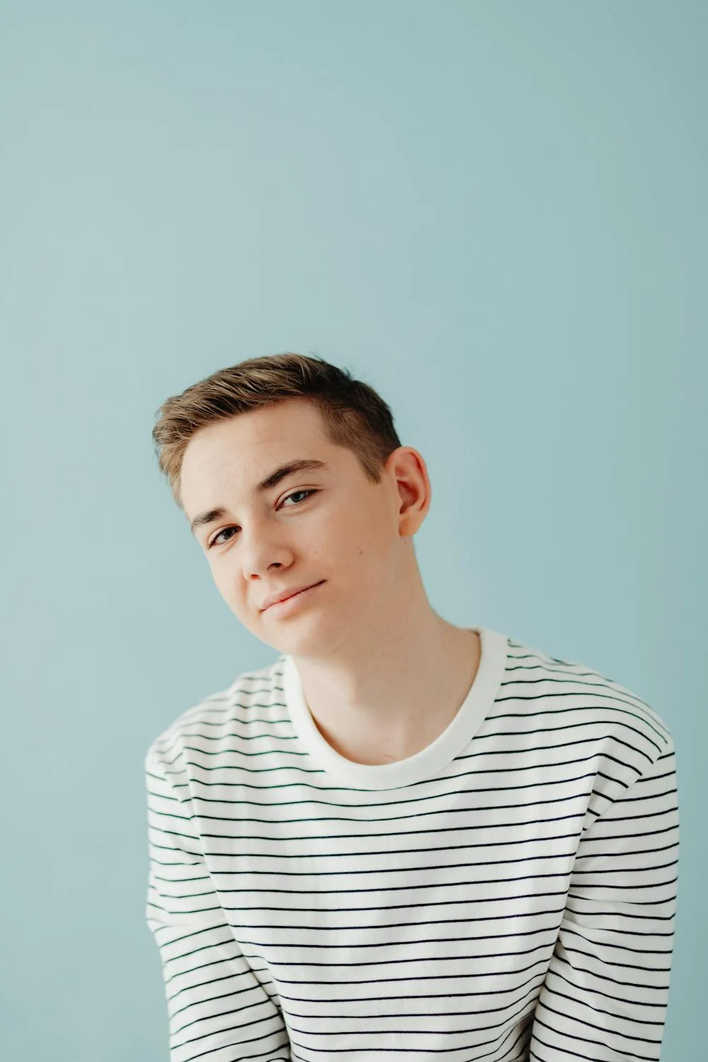 A smiling boy against a blue backdrop | Source: Pexels