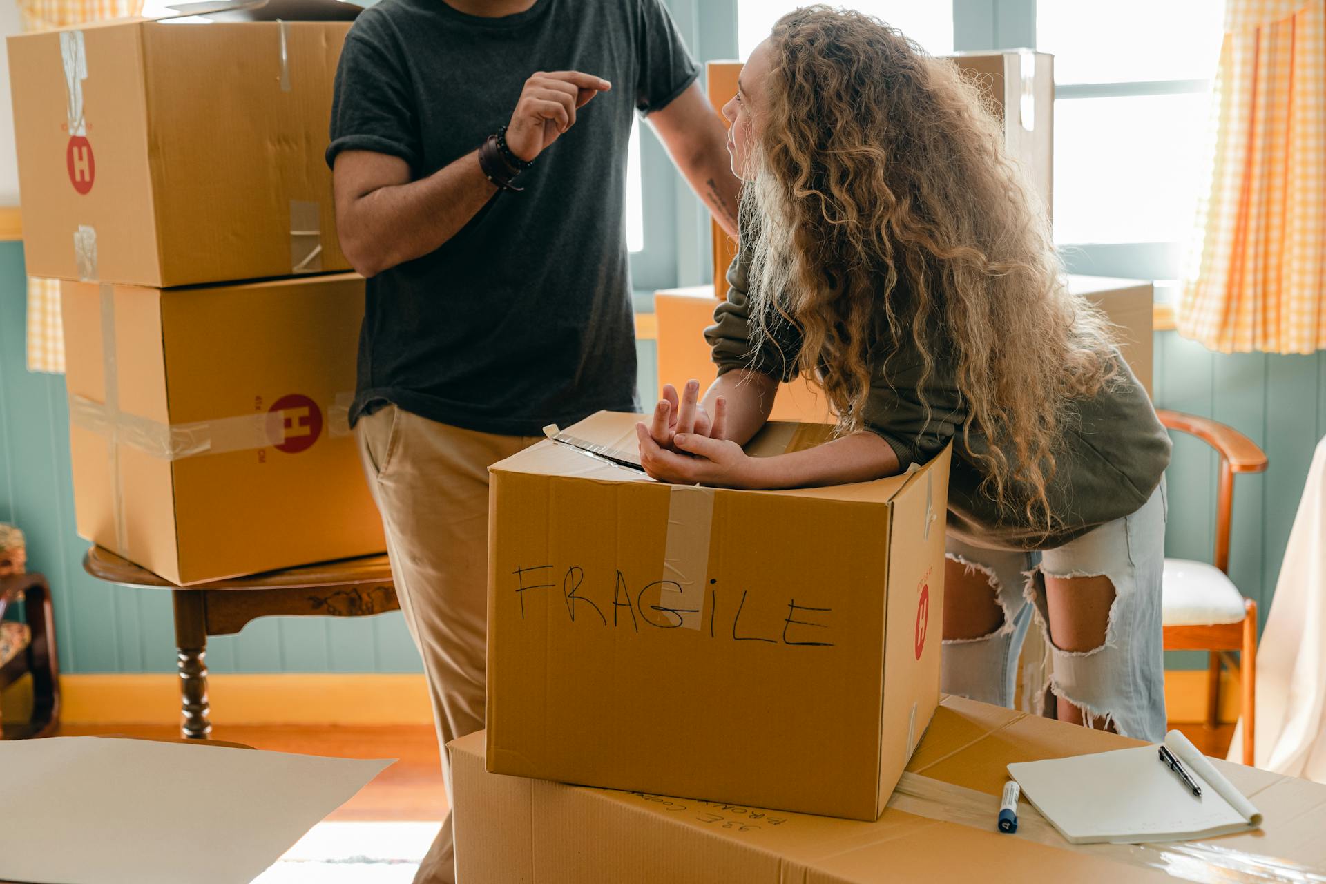 A couple talking amid a stack of packed cardboard boxes | Source: Pexels