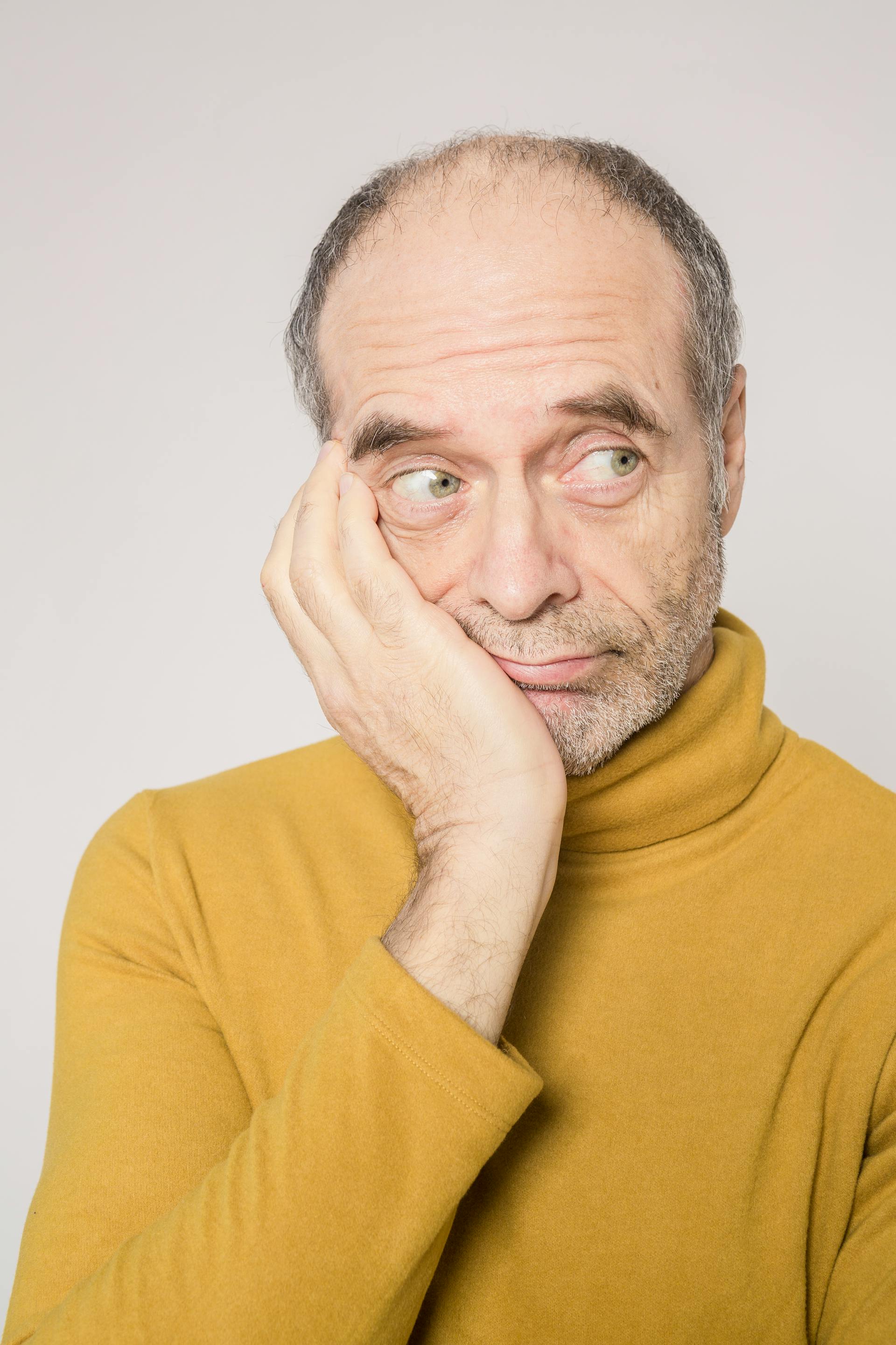 A senior man in a yellow sweater looking sideways | Source: Pexels