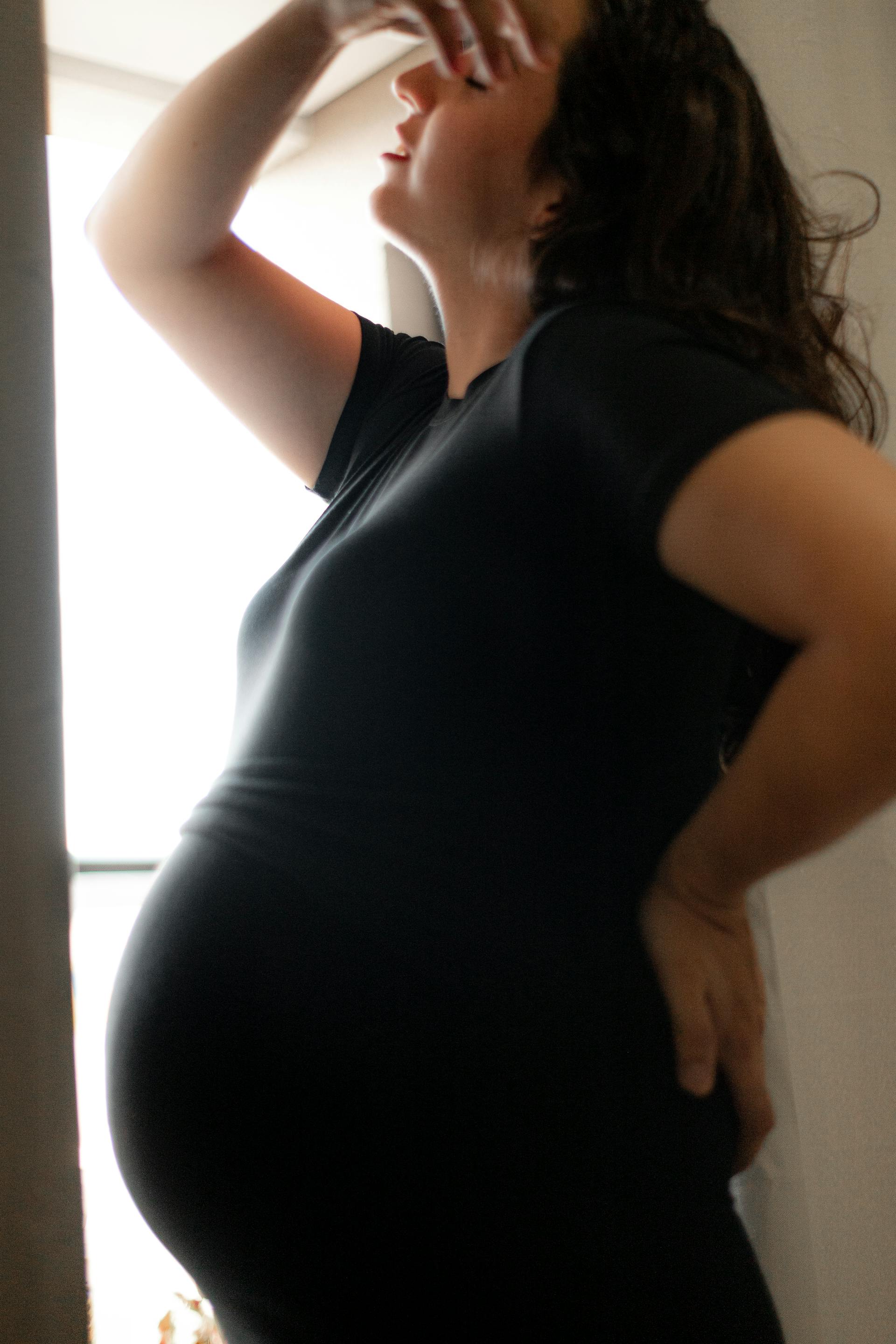 A distraught pregnant woman standing by the window | Source: Pexels