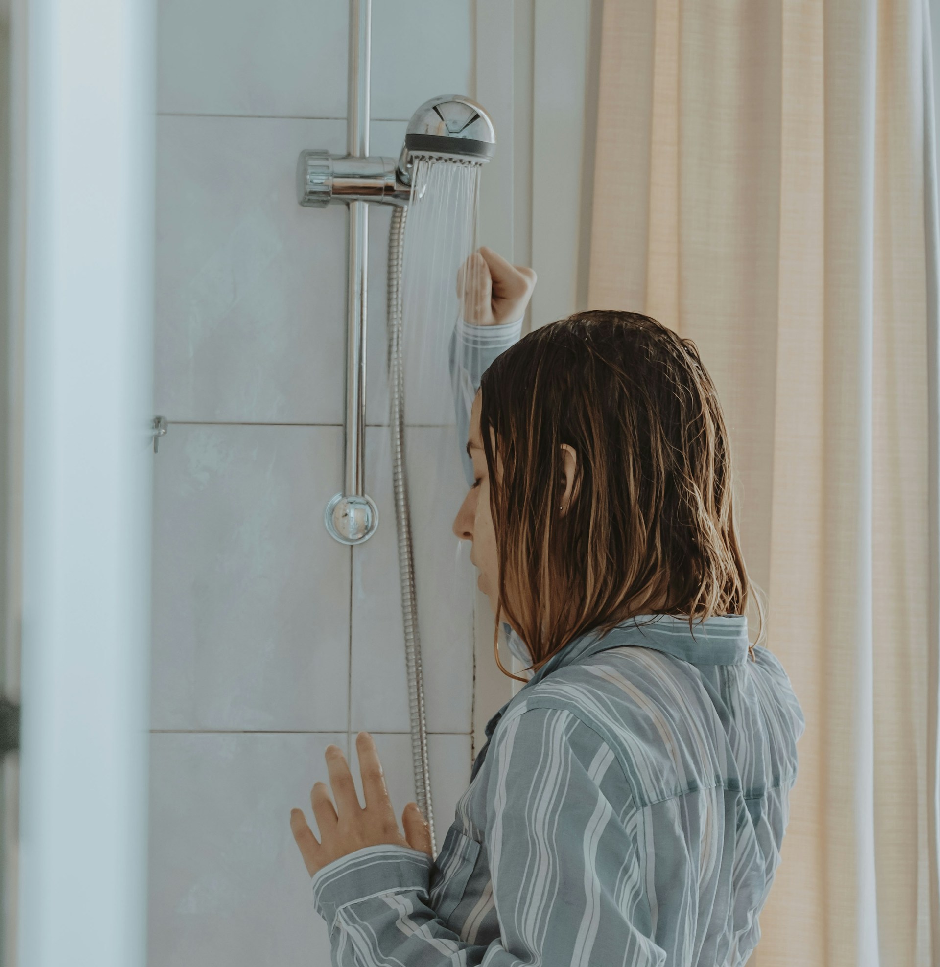 A depressed and desperate young lady standing in the shower | Source: Unsplash