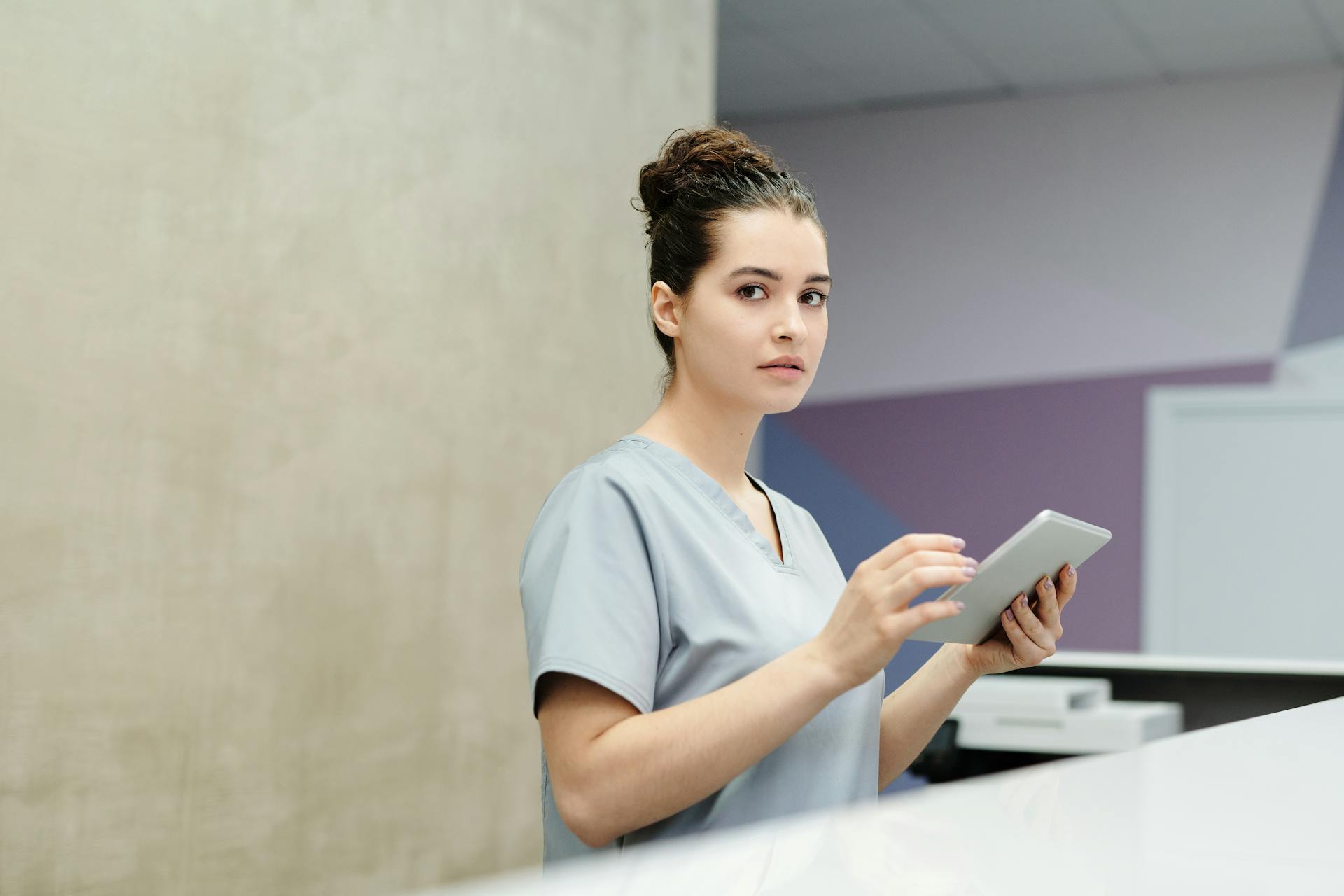 Une réceptionniste tenant une tablette dans un hôpital | Source : Pexels