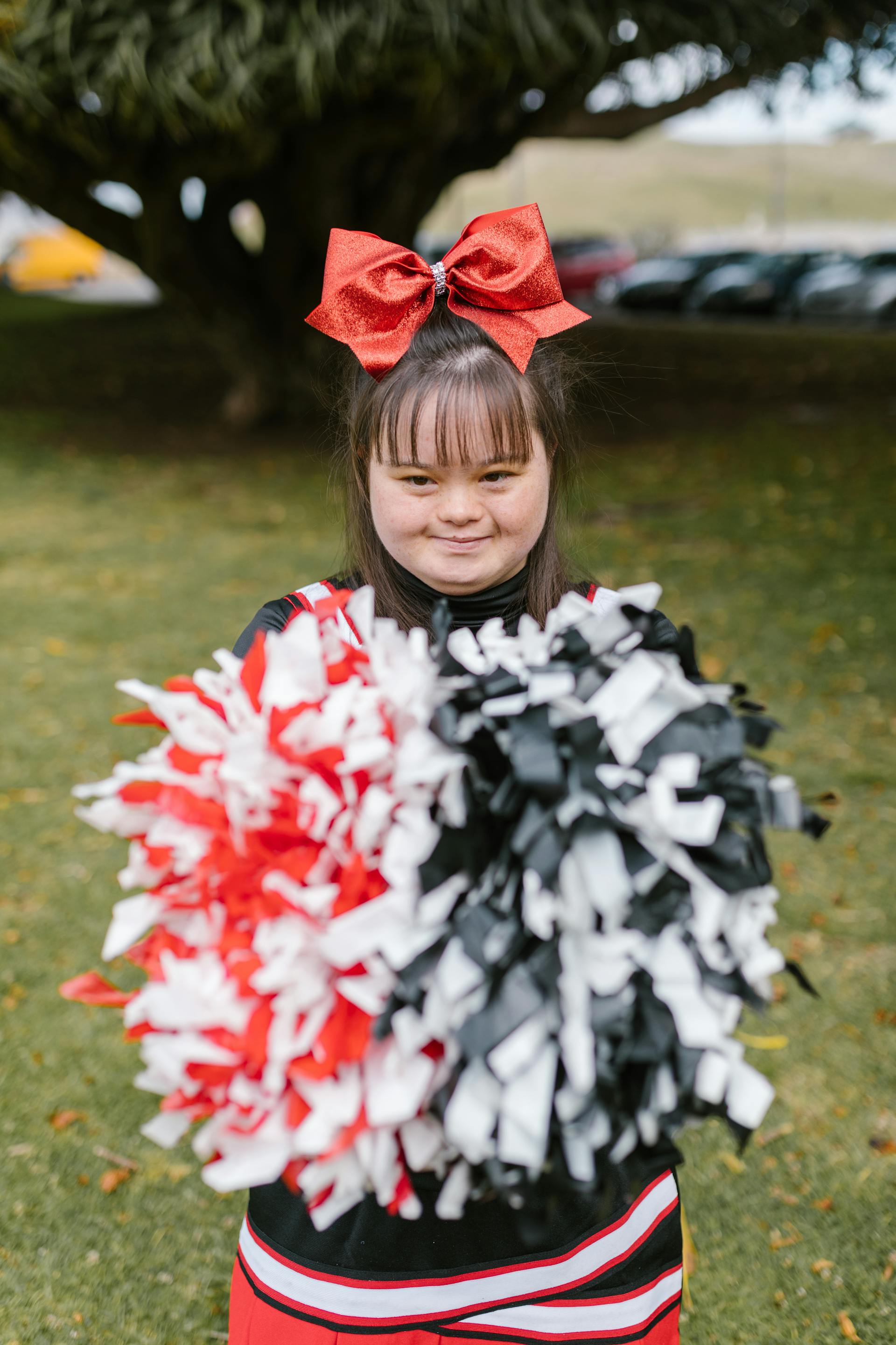 A young girl with Down syndrome in a cheerleader outfit and holding pompoms | Source: Pexels