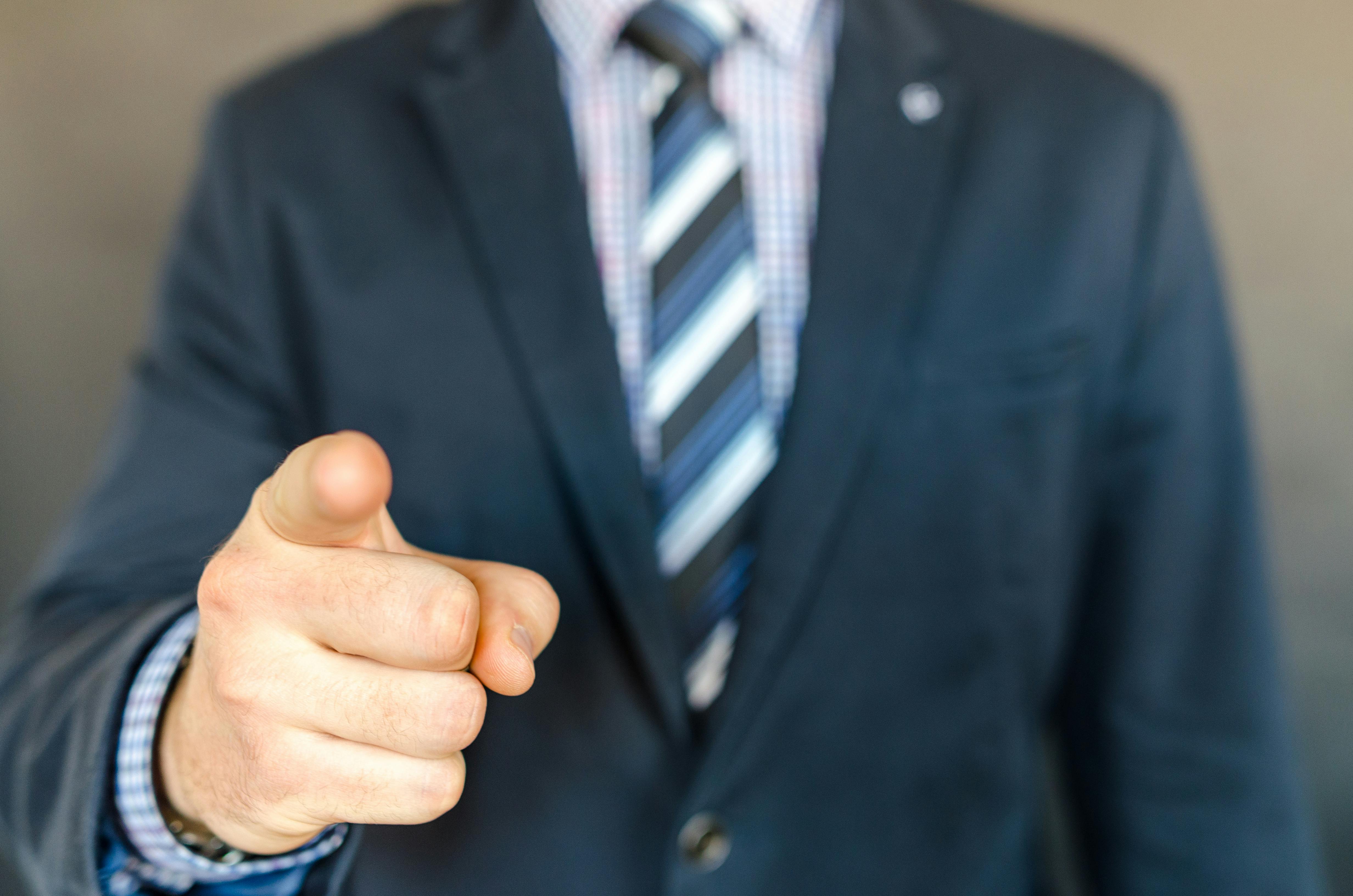 Man in a suit pointing his finger at someone off camera | Source: Pexels
