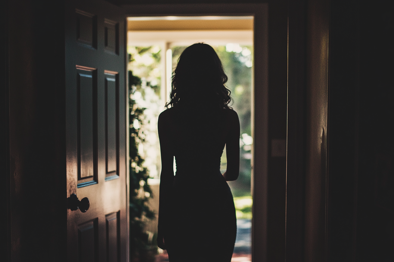 A woman silhouetted in a doorway | Source: Midjourney