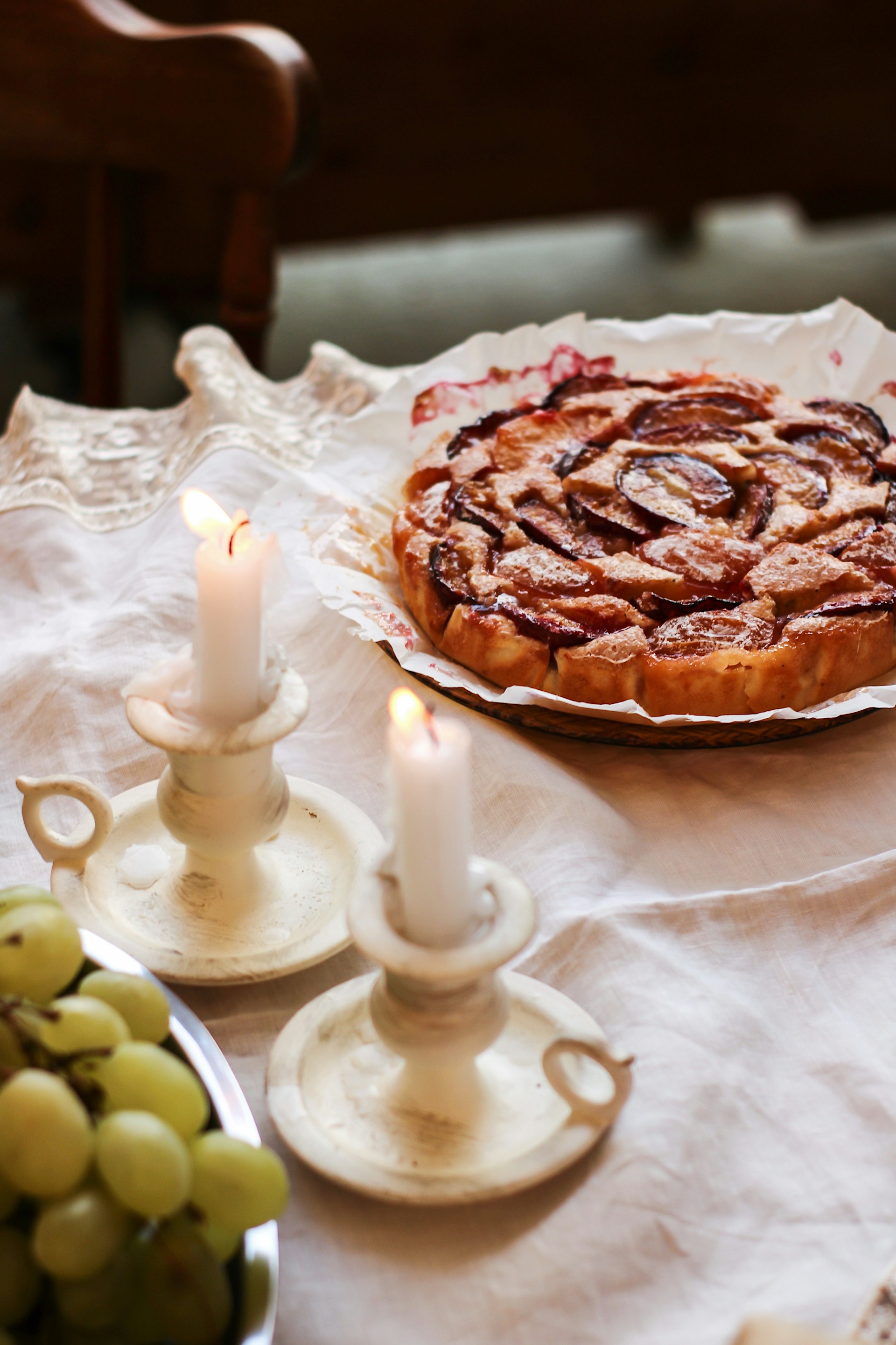 A bowl of grapes, candles, and a plate of pie on the table | Source: Unsplash