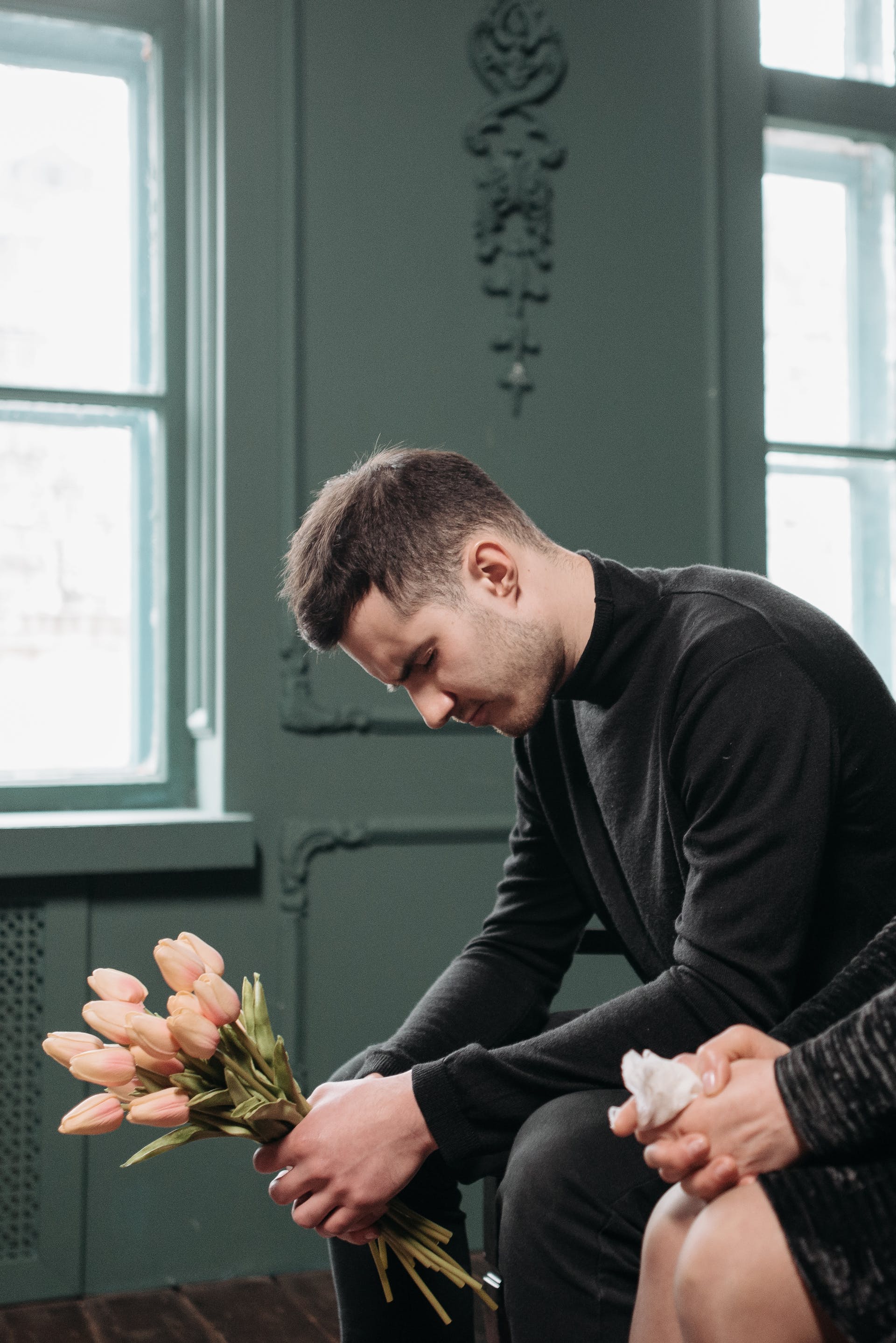 A sad man on black holding flowers | Source: Pexels