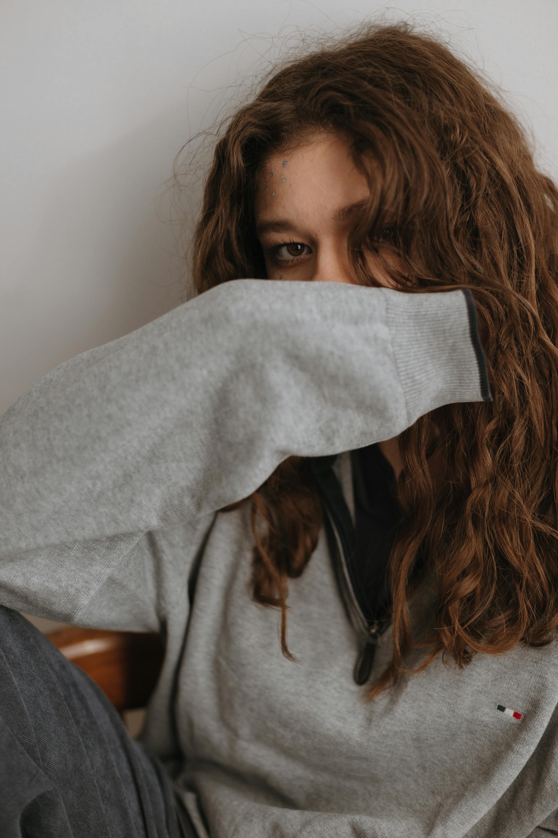 A sad young woman hiding her face with her arm | Source: Pexels