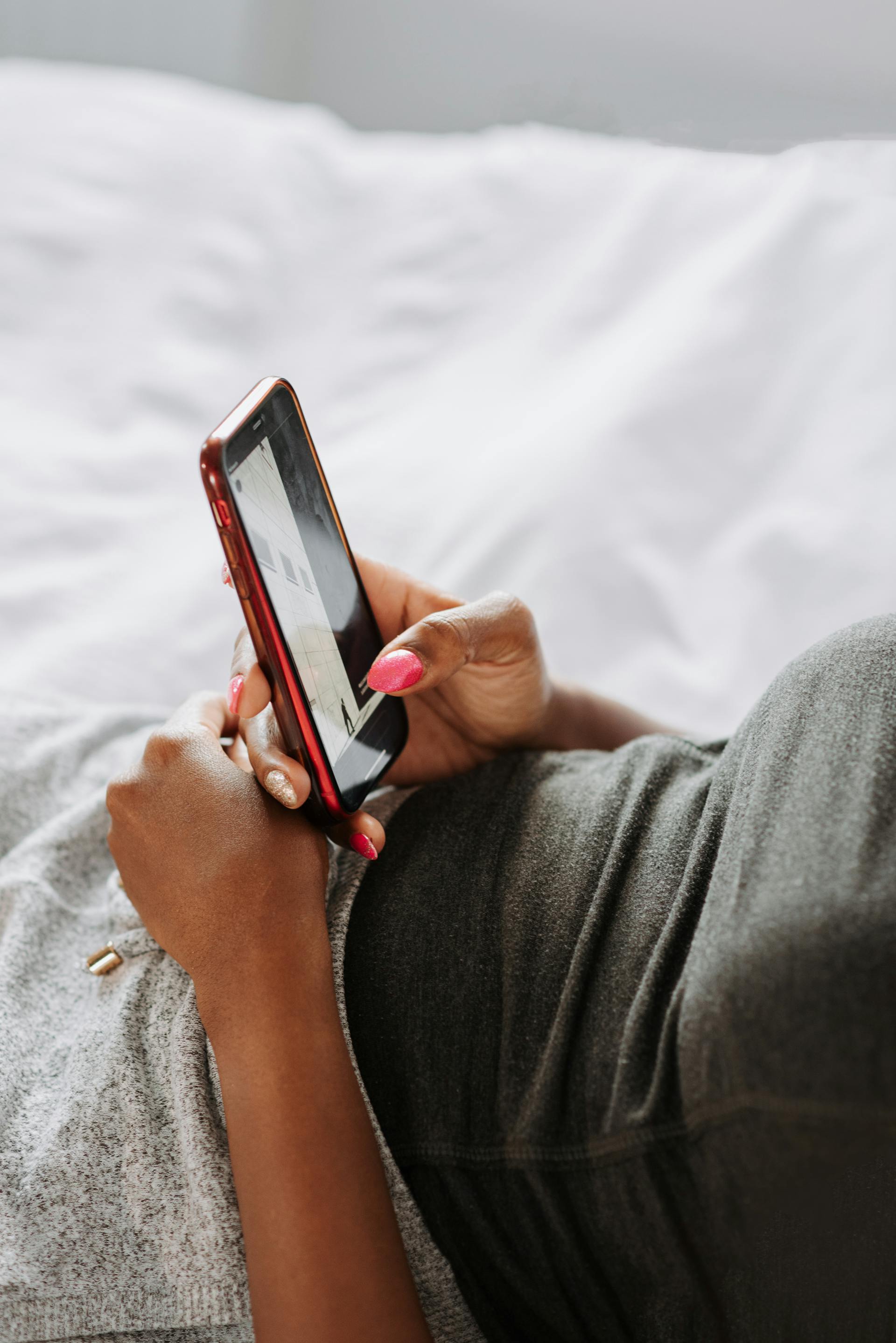 Uma mulher usando o telefone na cama | Fonte: Pexels