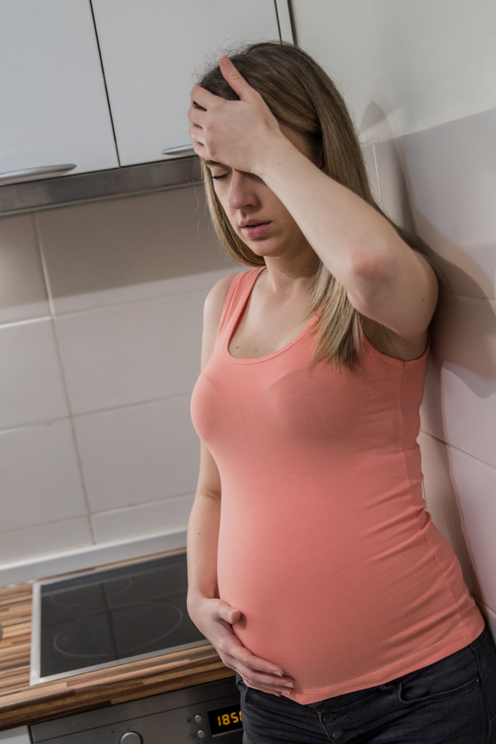 A stressed pregnant woman standing in the kitchen | Source: Freepik