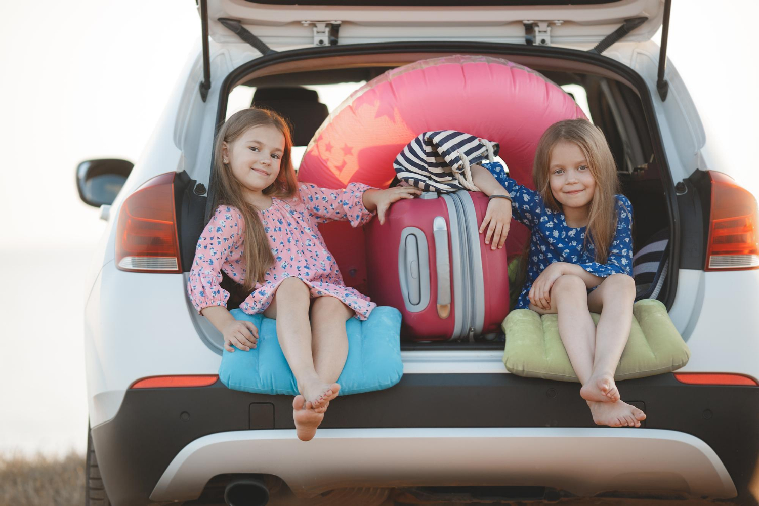 Two little girls sitting in a car trunk | Source: Freepik