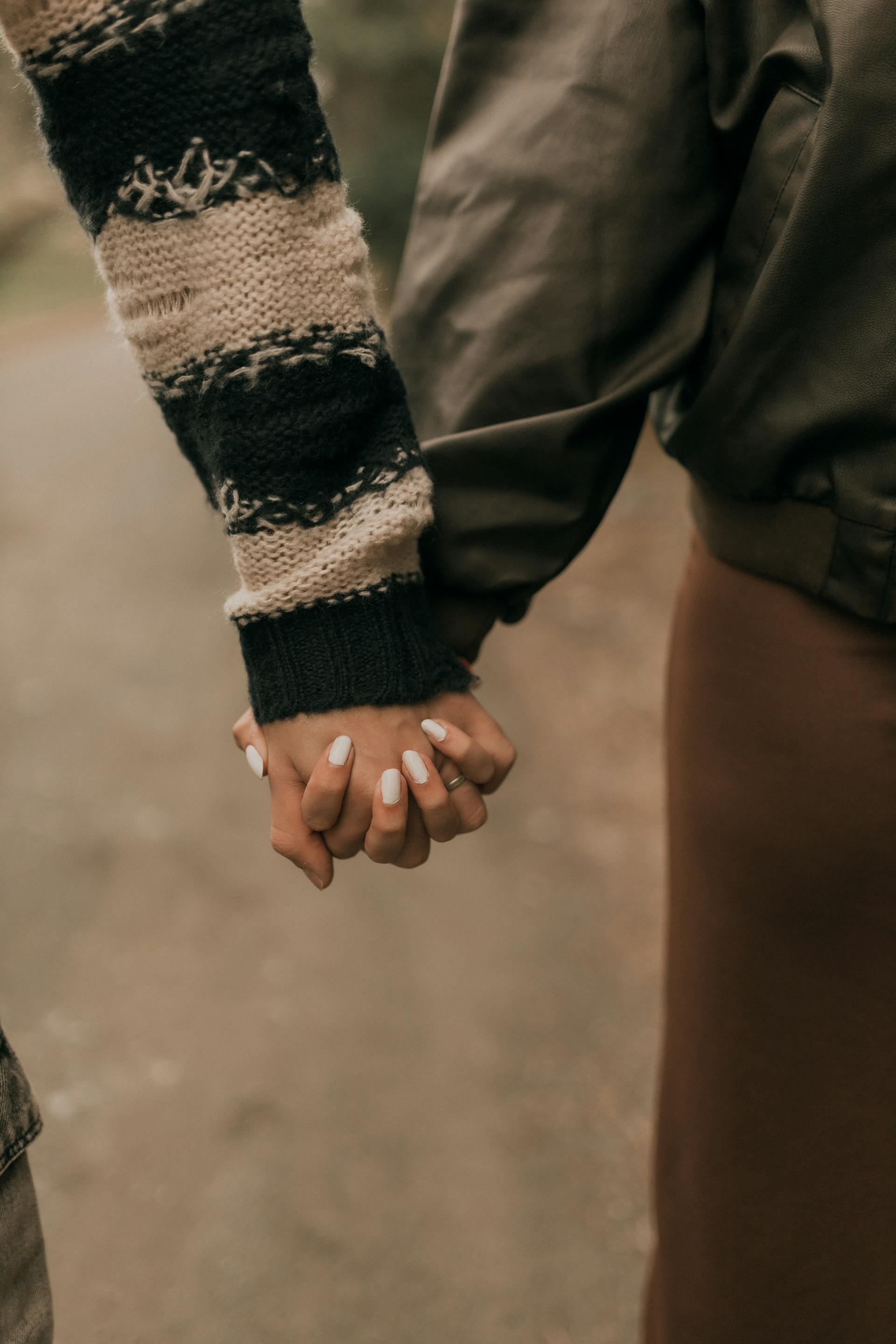 A close-up of a couple holding hands outdoors | Source: Pexels