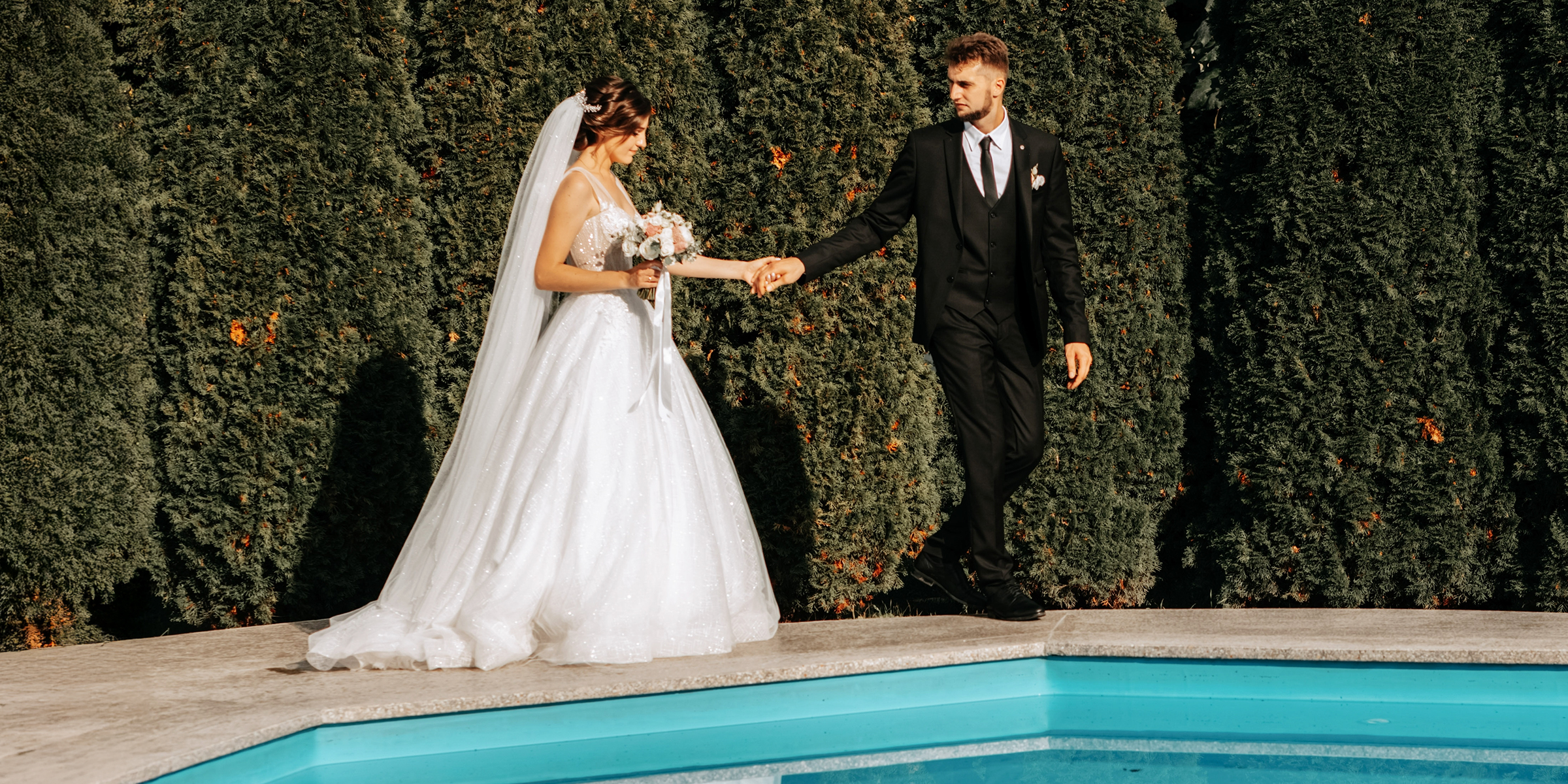 A bridal couple standing by a pool | Source: Shutterstock