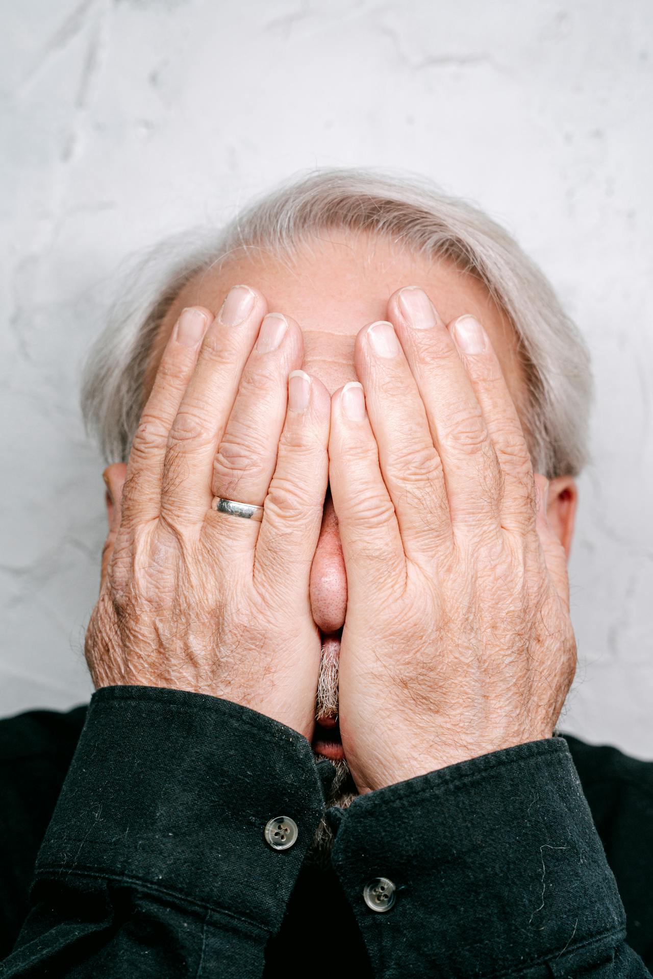 A distressed elderly man covering his face | Source: Pexels