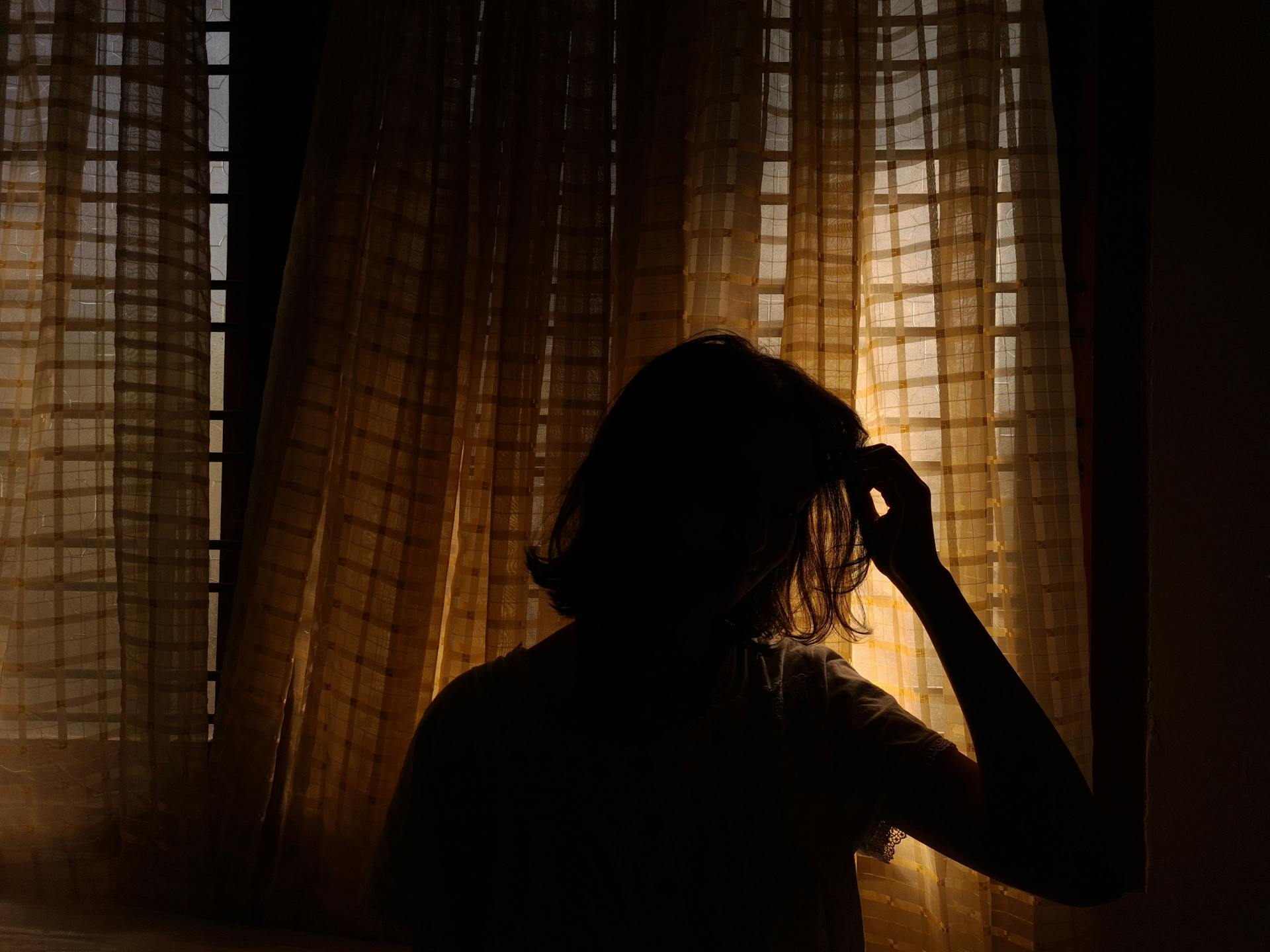 Silhouette of a woman standing by a window | Source: Pexels