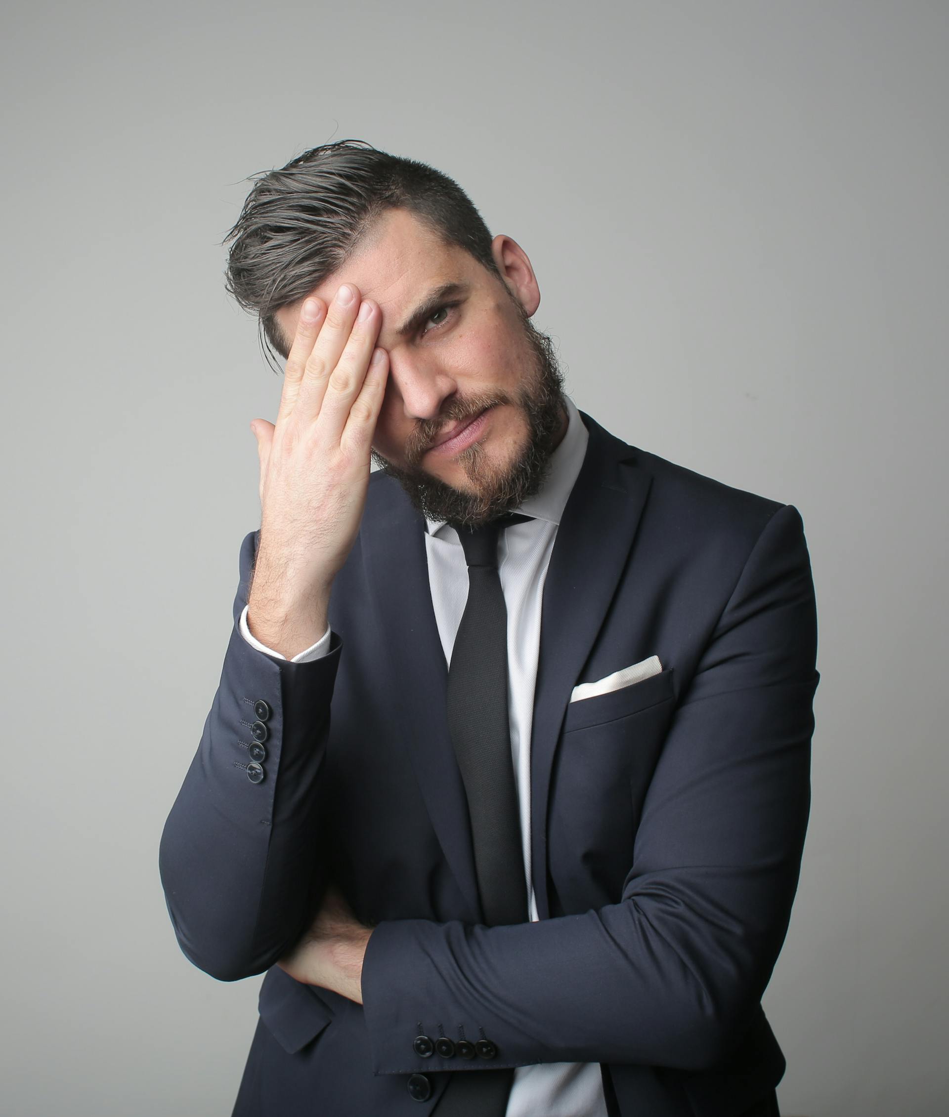 A serious man in a suit with his hand on his head | Source: Pexels