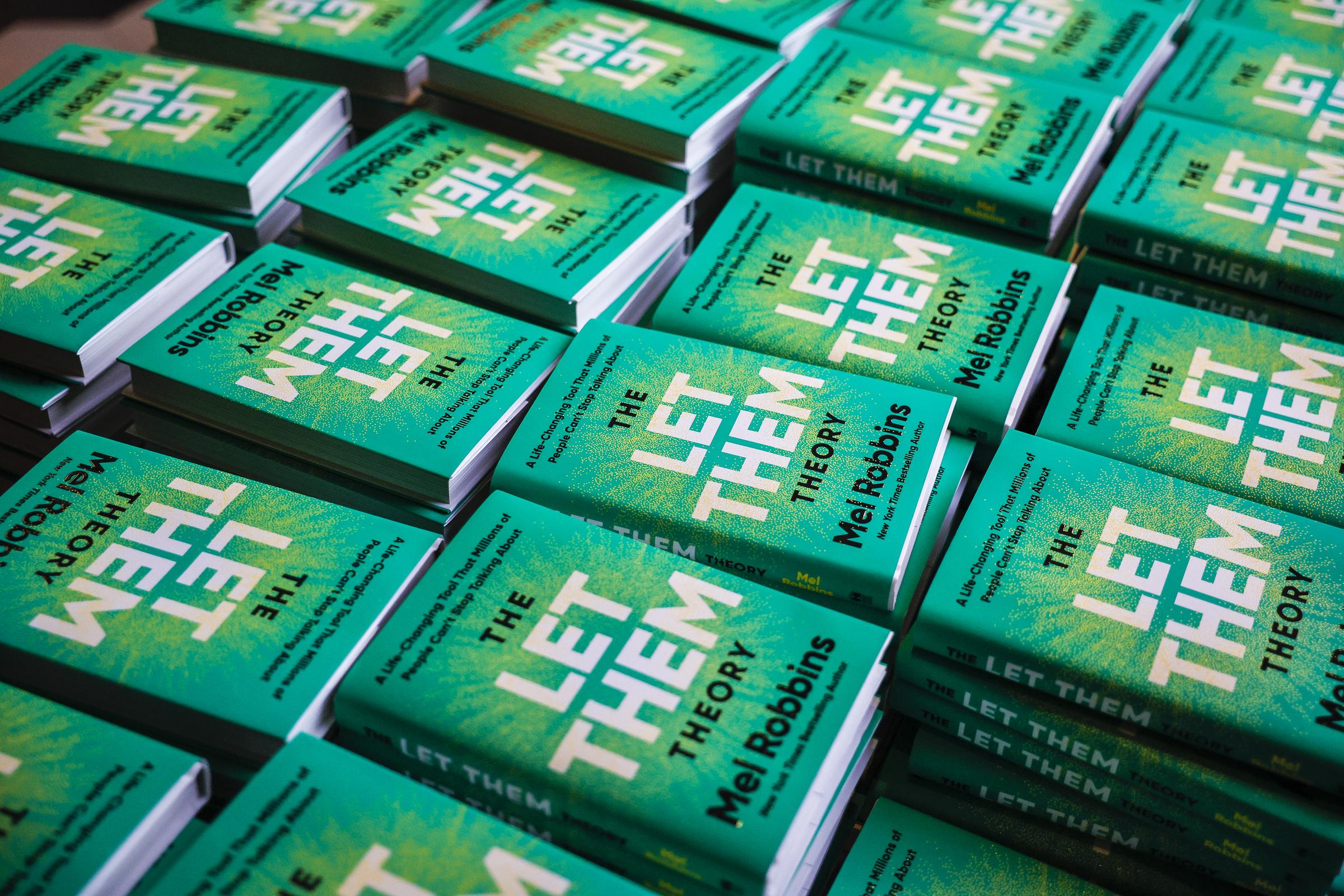 Copies of "The Let Them Theory" by Mel Robbins are displayed before a book signing at Big Night Live on January 22, 2025. | Source: Getty Images