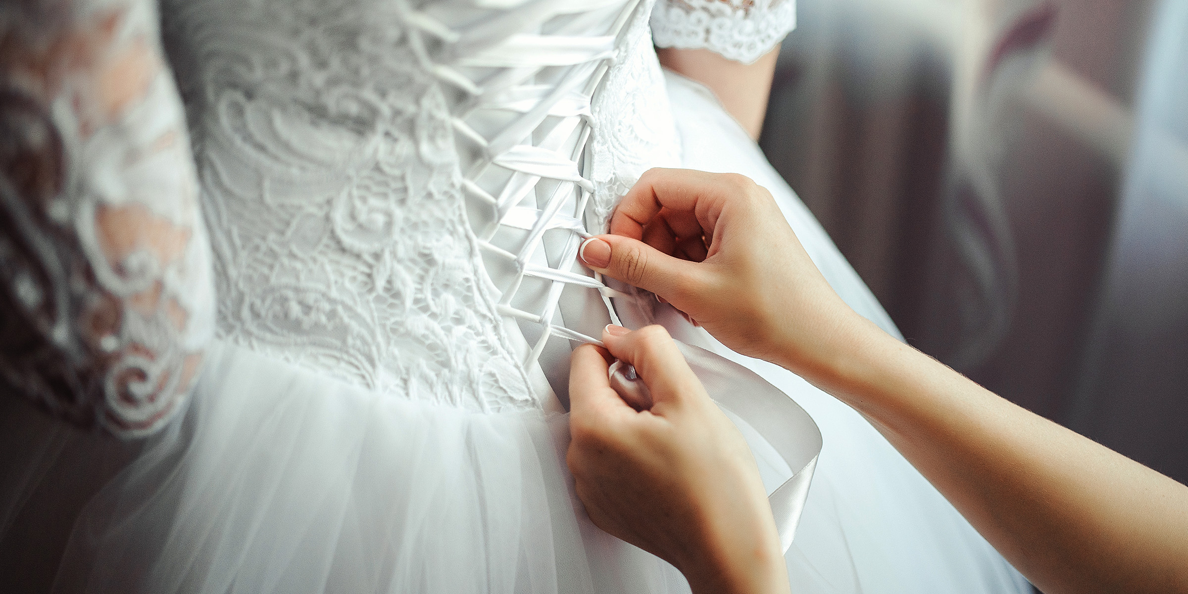 A woman lacing up the bodice on a wedding dress | Source: Freepik