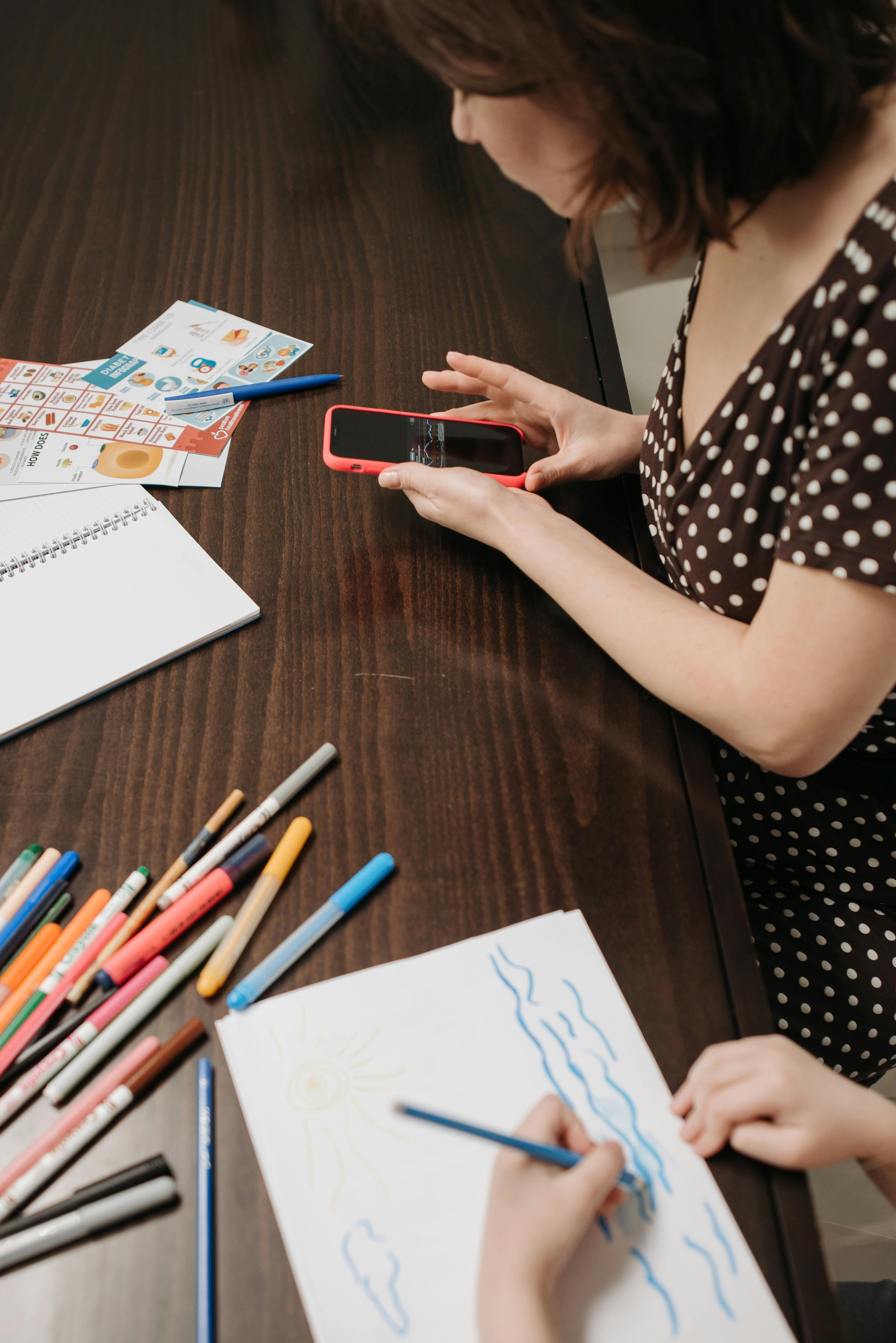 A child drawing next to their parent | Source: Pexels