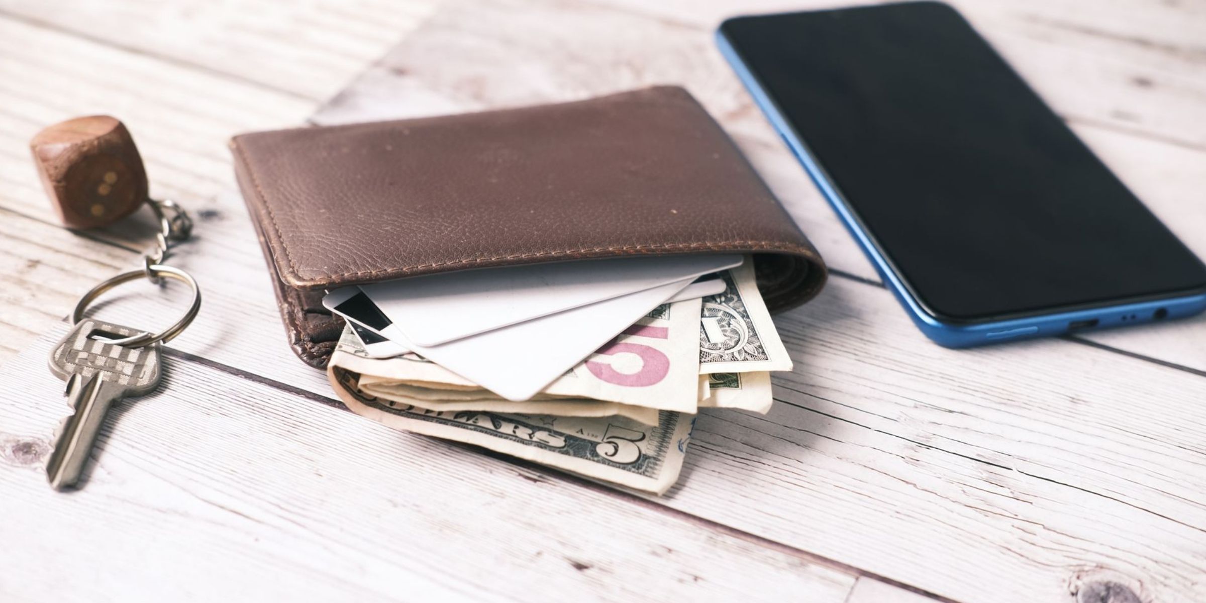 Wallet with cash and cards beside keys and a smartphone | Source: Pexels