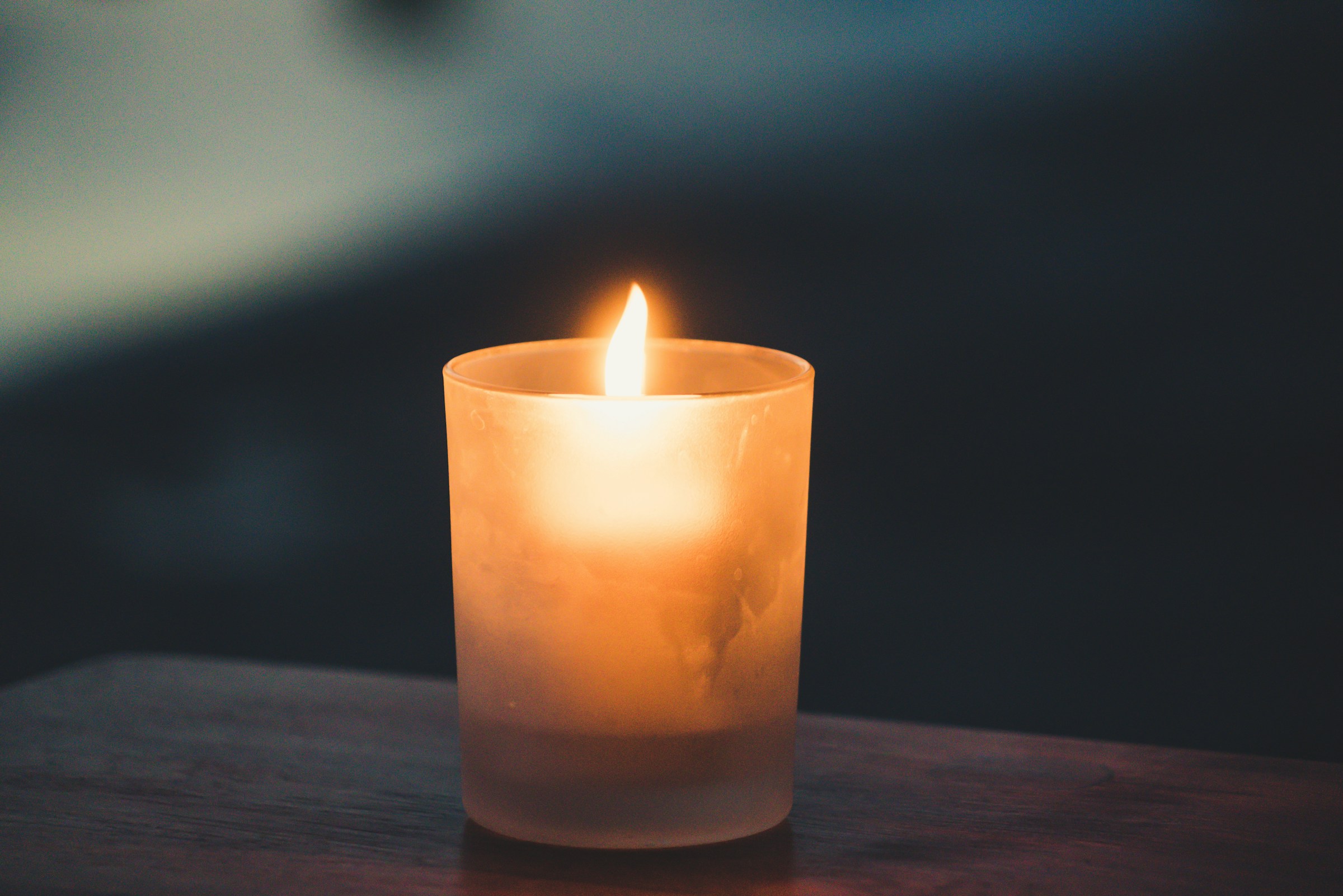 A lit candle on a wooden surface | Source: Unsplash