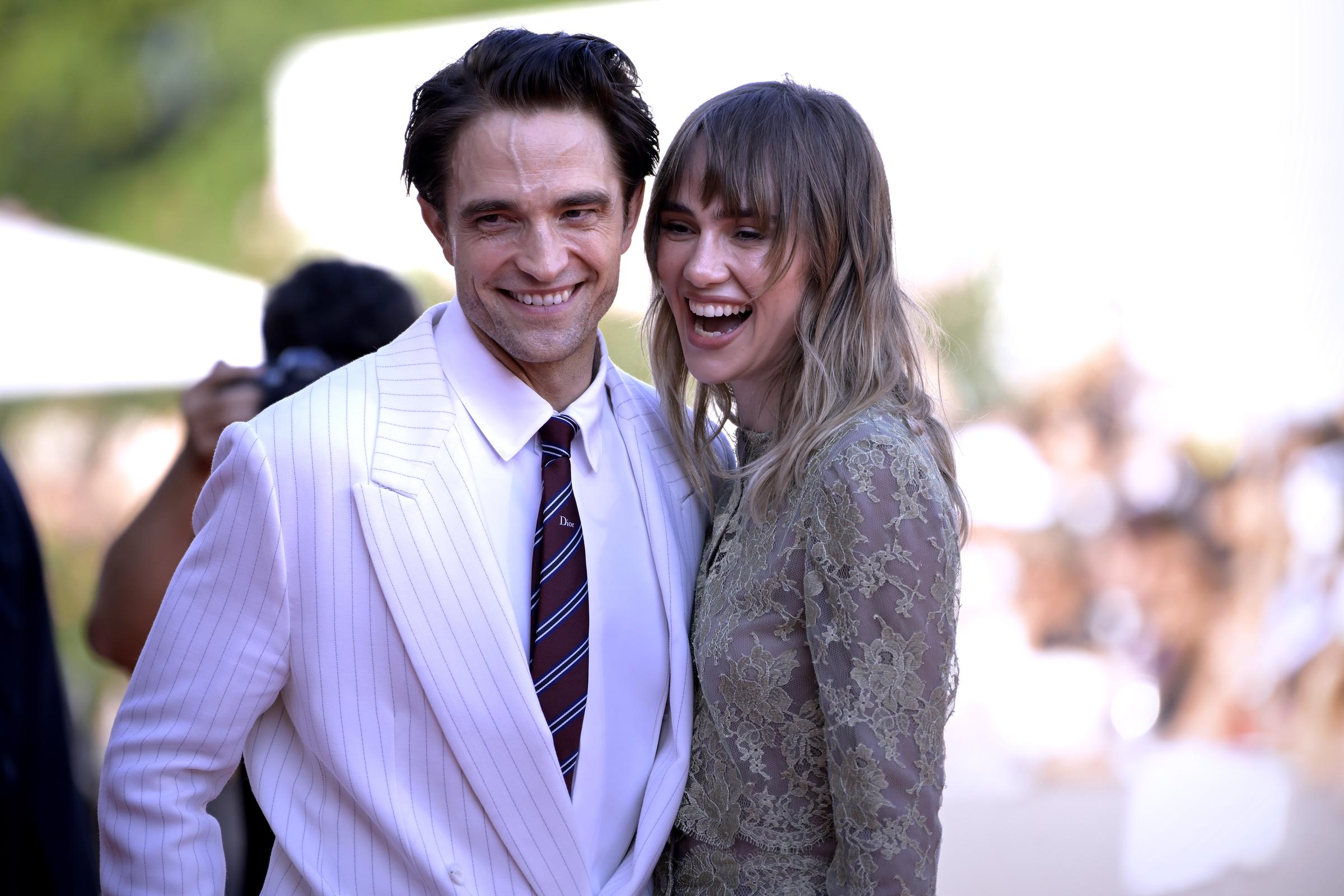 Robert Pattinson and Suki Waterhouse pose closely together as they greet photographers, offering a closer view of their coordinated festival style. | Source: Getty Images