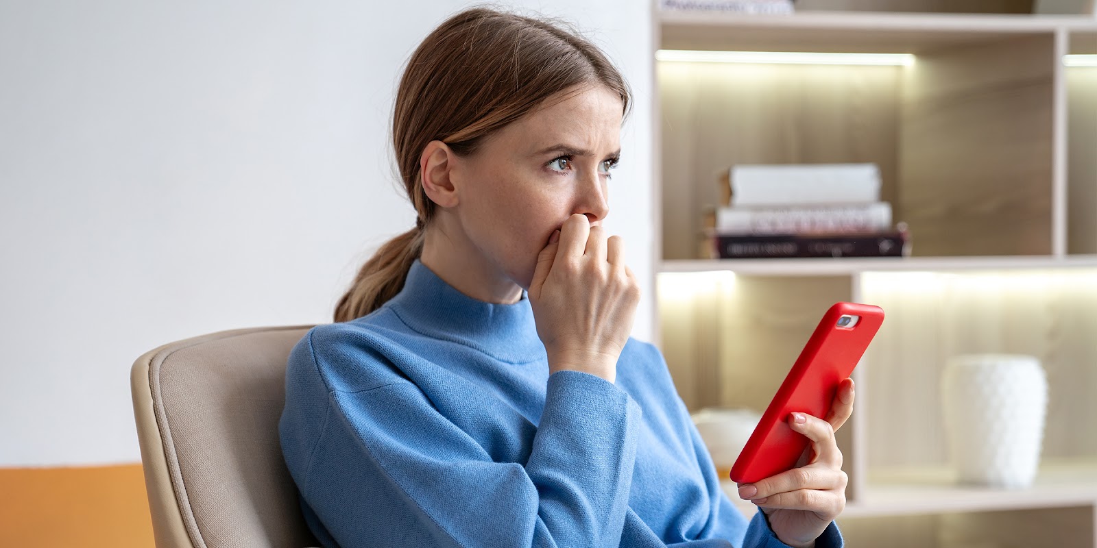 A thoughtful woman sitting with a phone in her hand | Source: Shutterstock