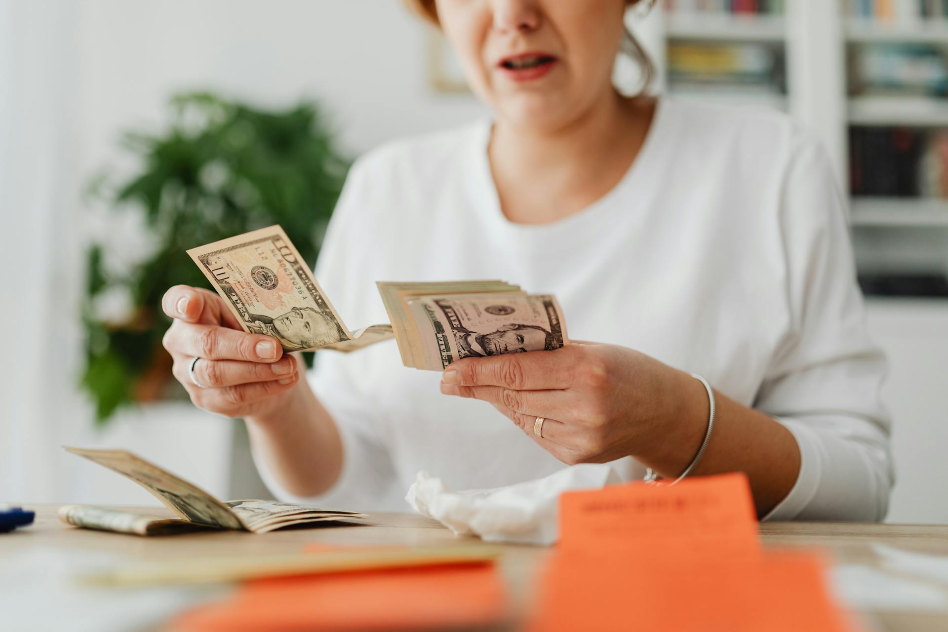 A woman sitting on a chair and counting money | Source: Pexels