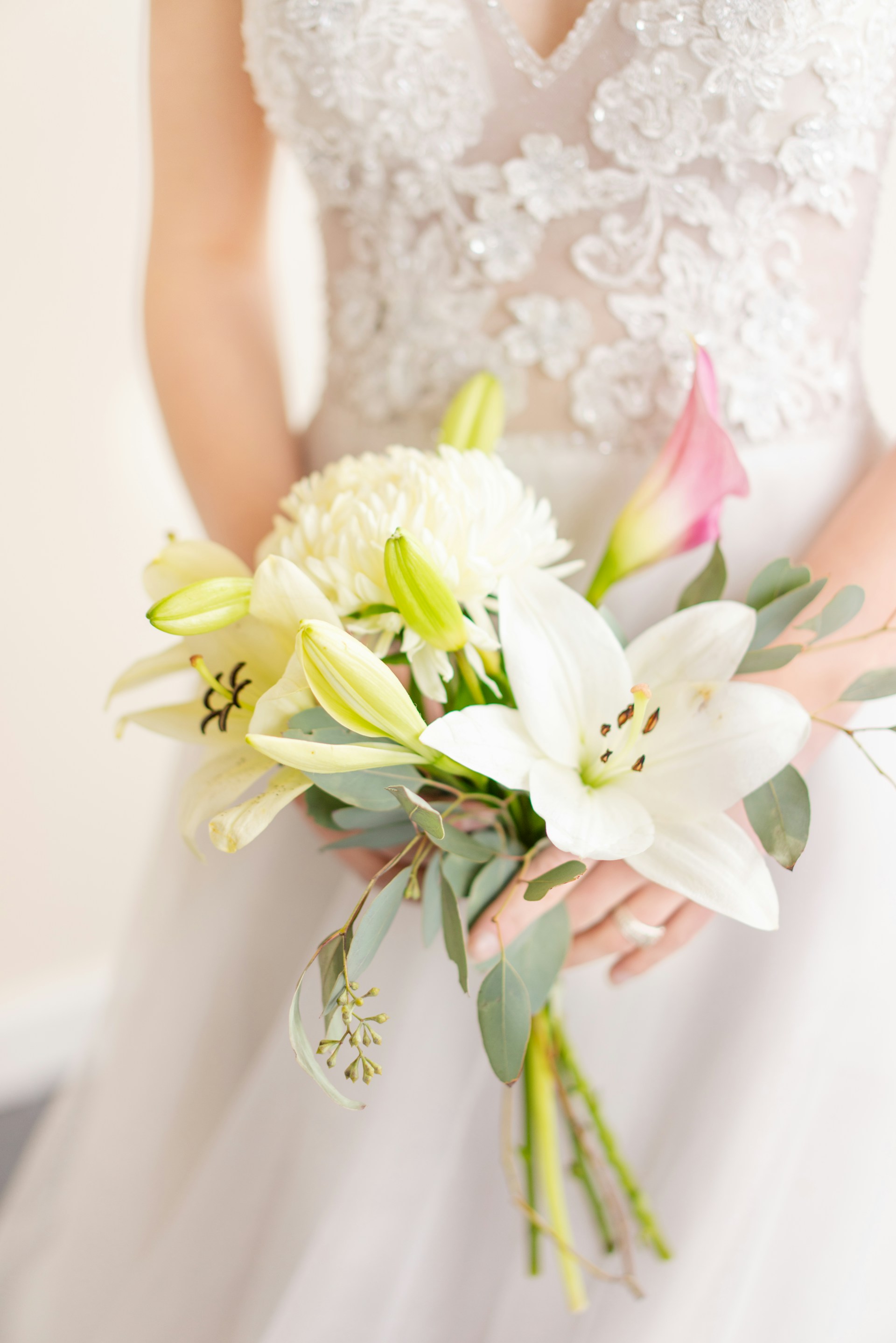 Gros plan recadré d'une mariée tenant un bouquet de lys | Source : Unsplash