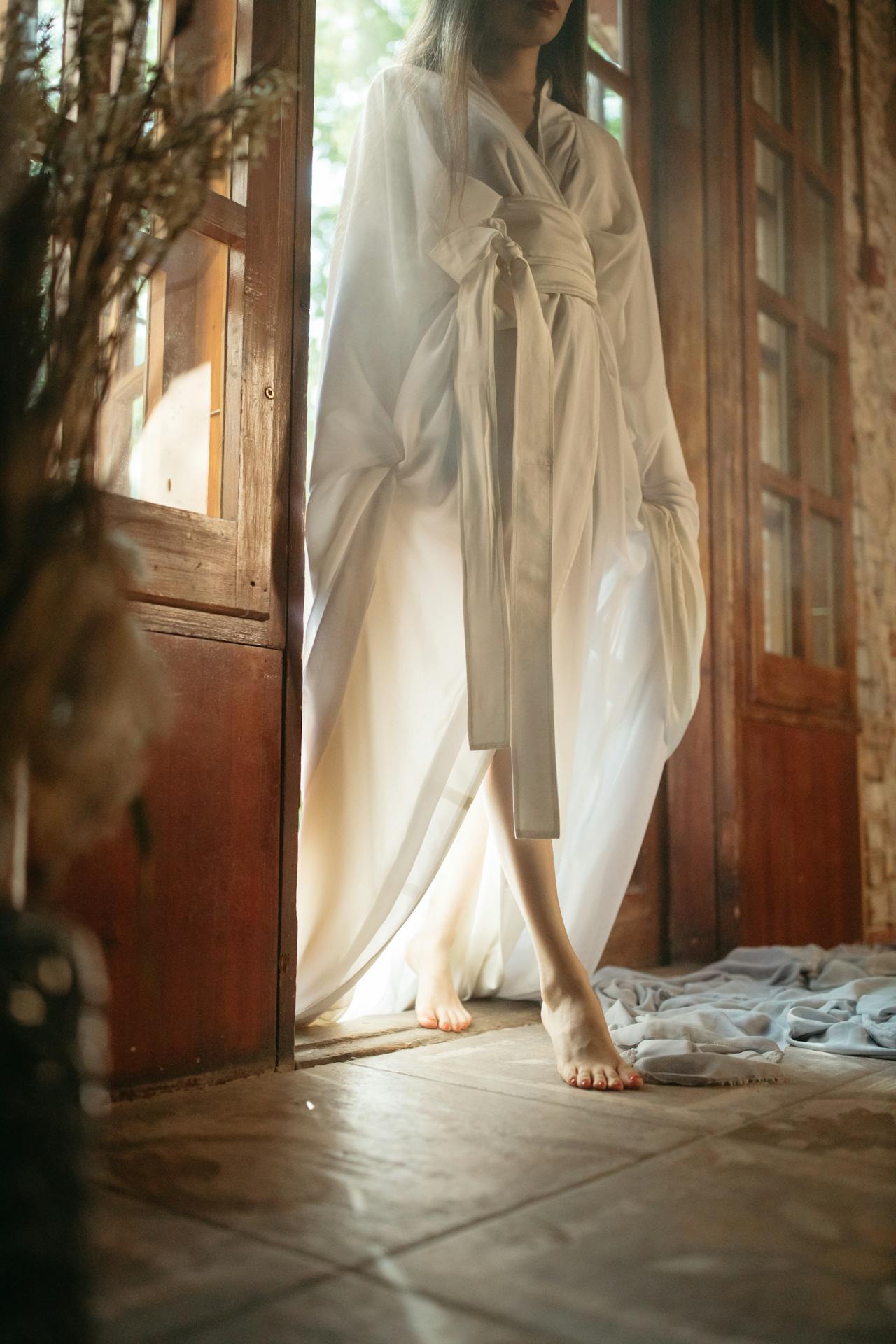 A woman in a white robe standing at the doorway | Source: Pexels