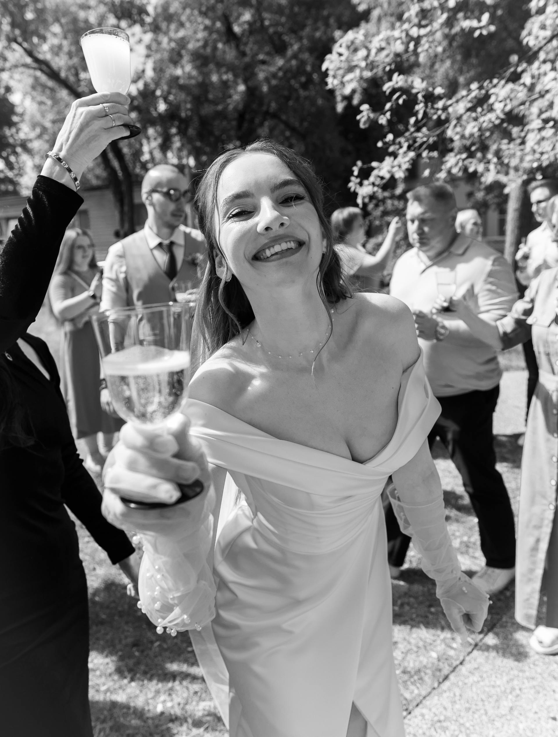 Ujęcie uśmiechniętej panny młodej z drinkiem w dłoni w skali szarości | Źródło: Pexels