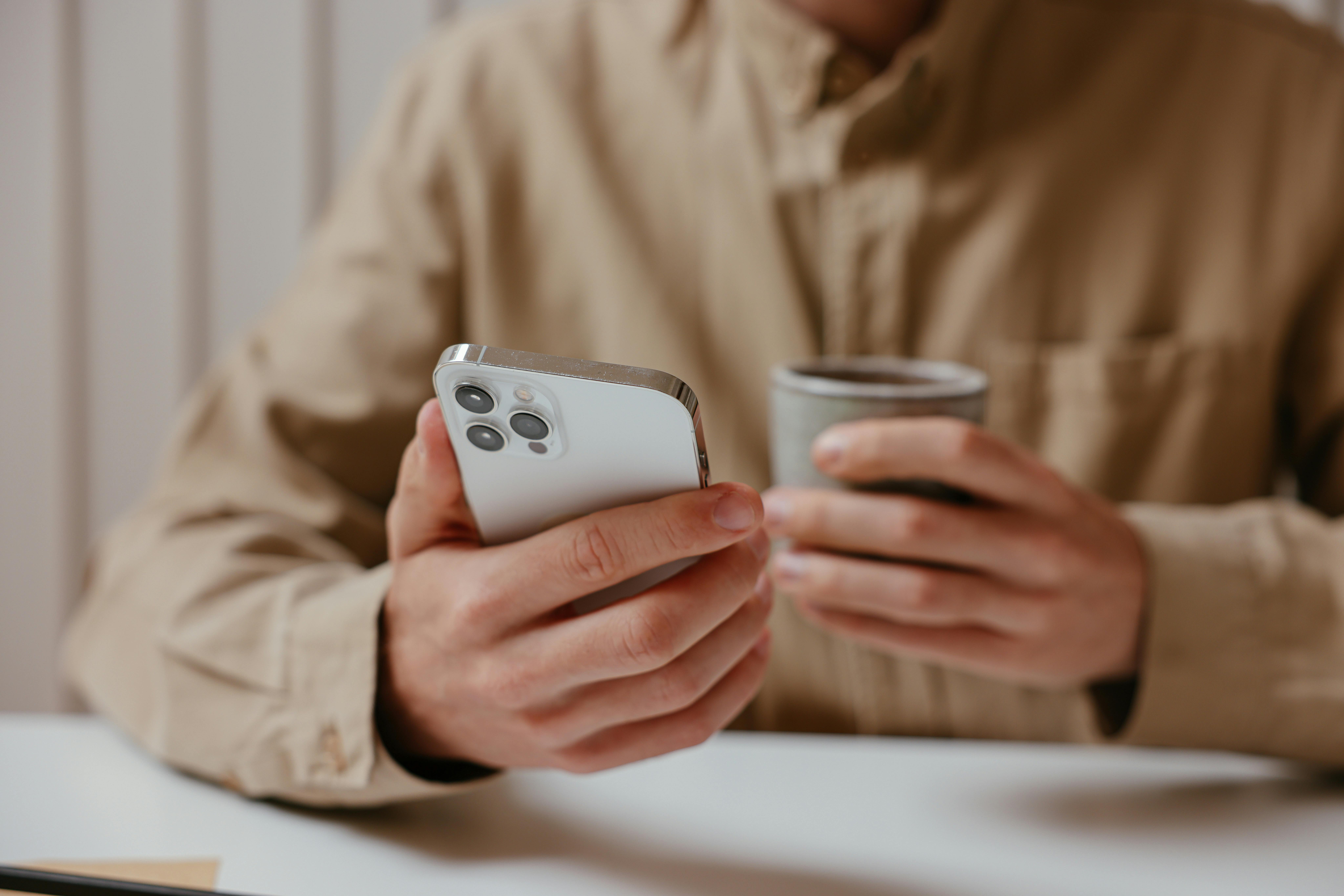 A man holding a phone and a cup of coffee | Source: Pexels