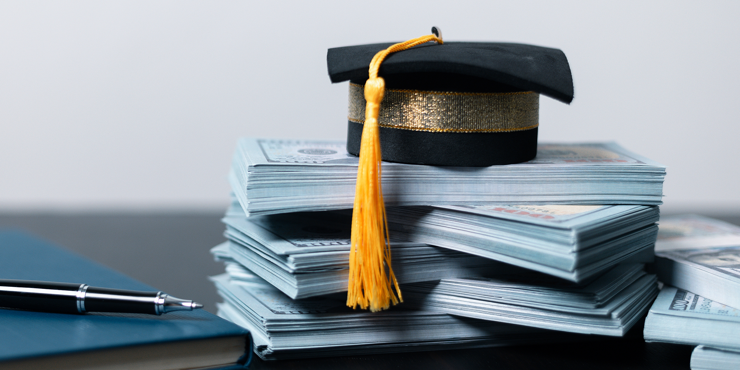 A graduation cap placed atop stacks of cash | Source: Shutterstock
