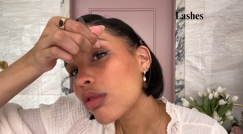 Nara Smith doing her makeup routine from a video dated December 12, 2024. | Source: YouTube/Vogue