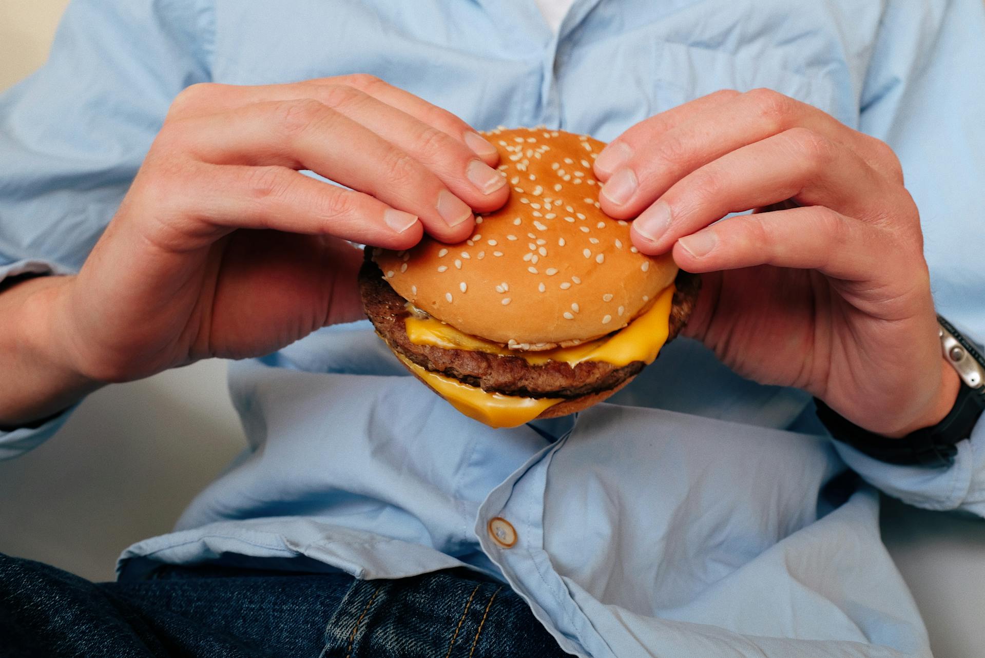 Close-up cropped shot of a man holding a burger | Source: Pexels