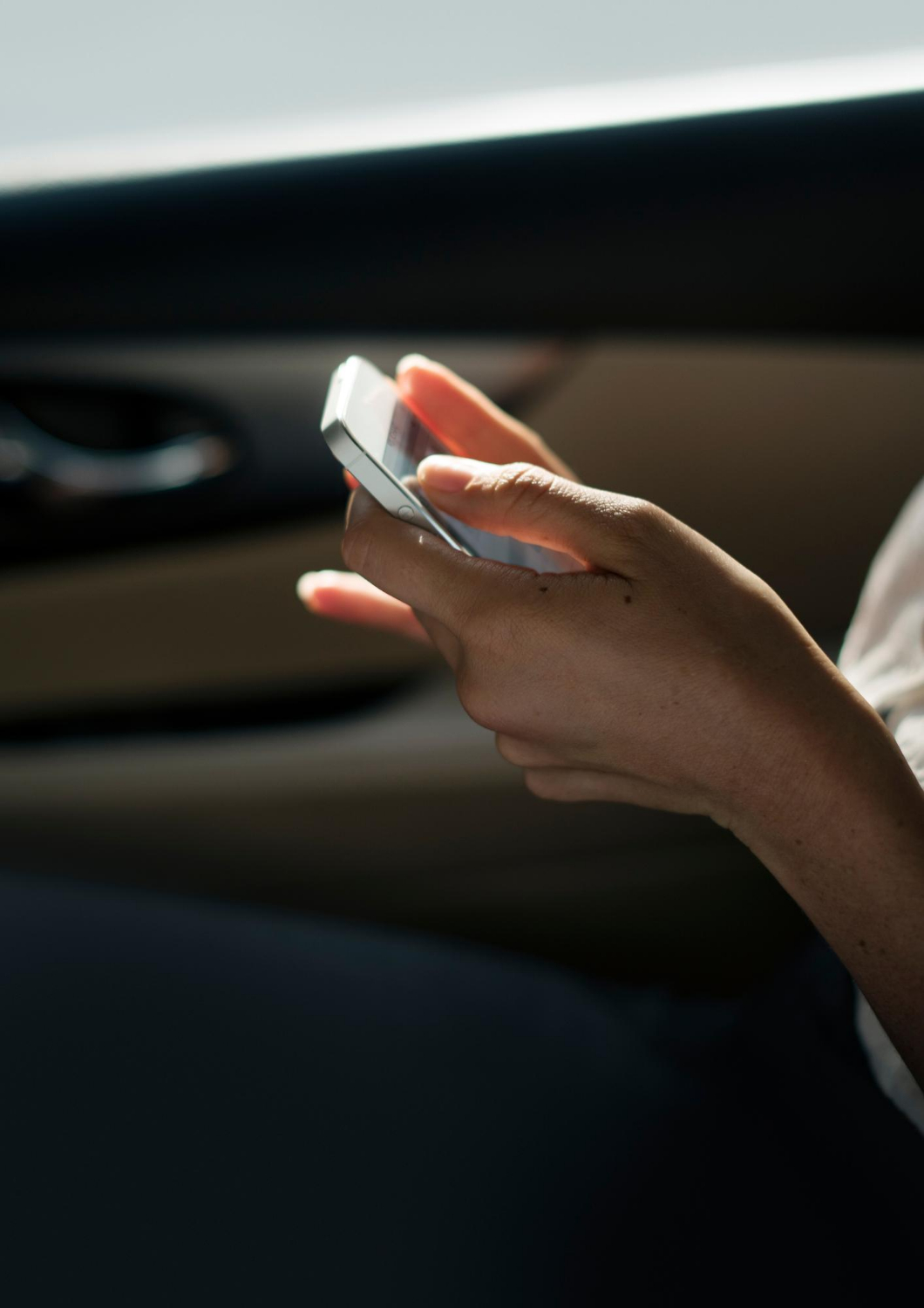 A woman holding her phone while seated in a car | Source: Freepik