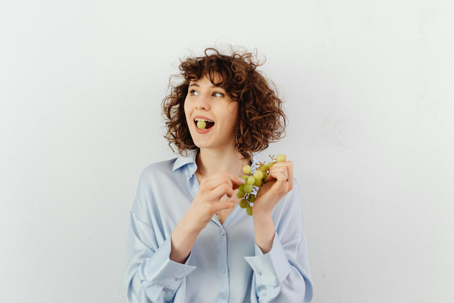 A curly-haired woman eating grapes | Source: Pexels