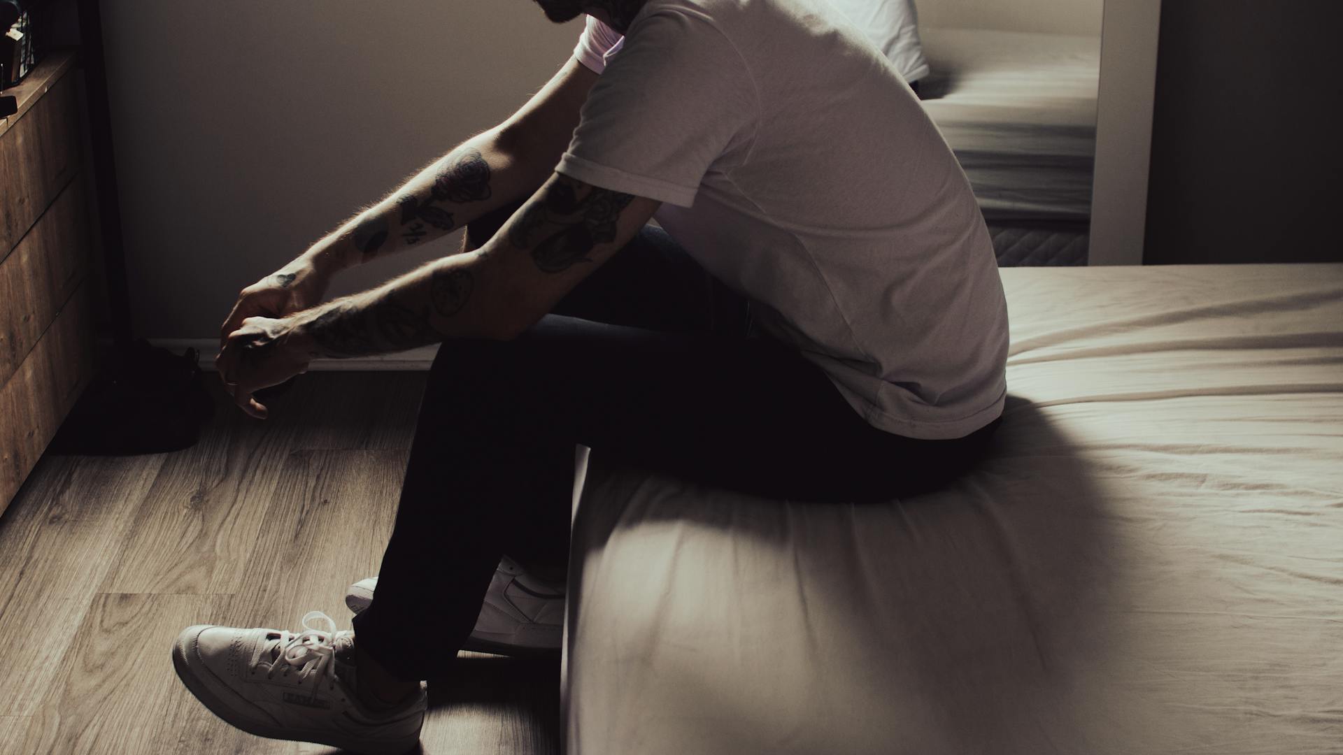 A close-up shot of a man sitting on the bed's corner | Source: Pexels