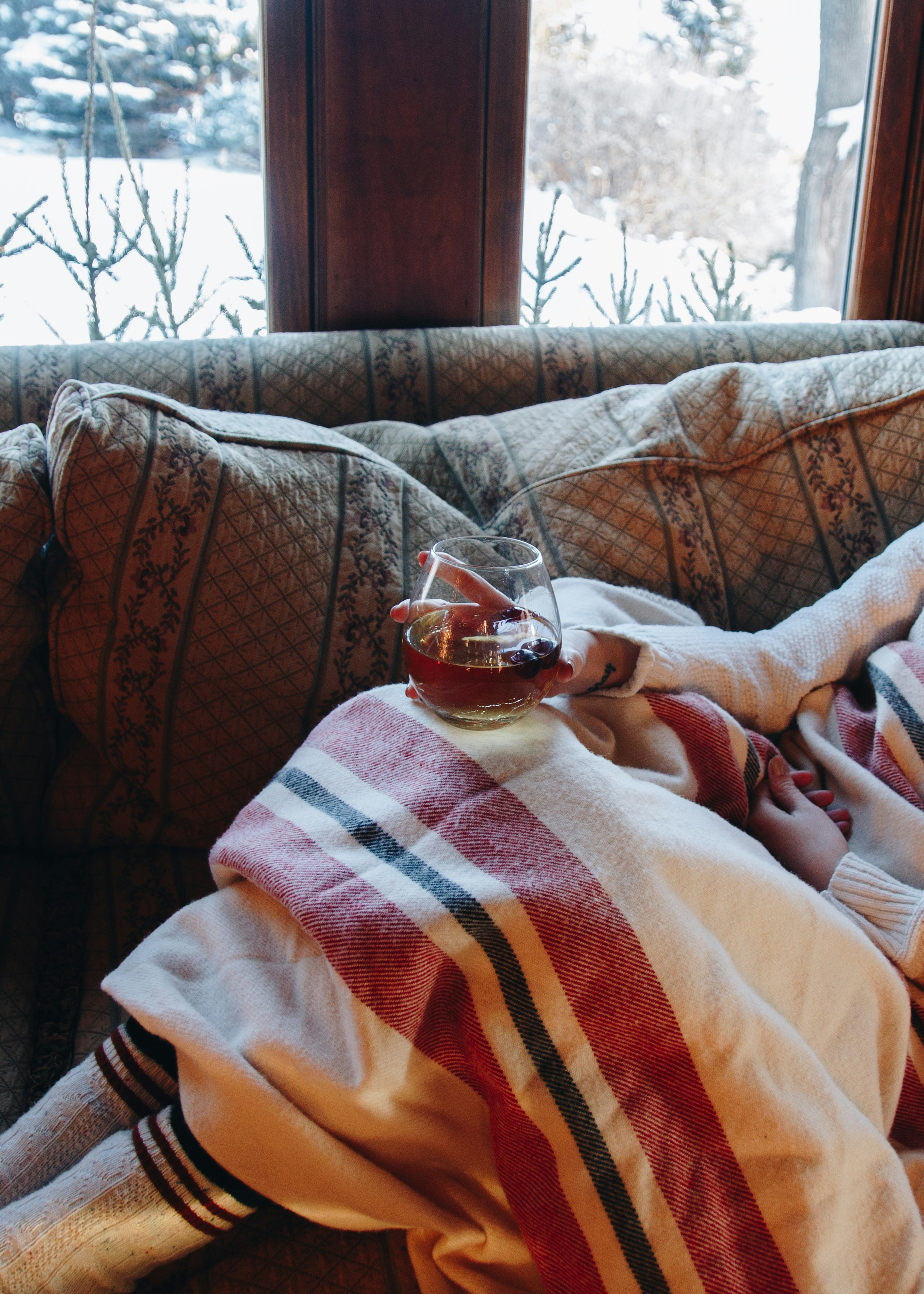 A woman covered in a blanket while drinking a beverage | Source: Unsplash