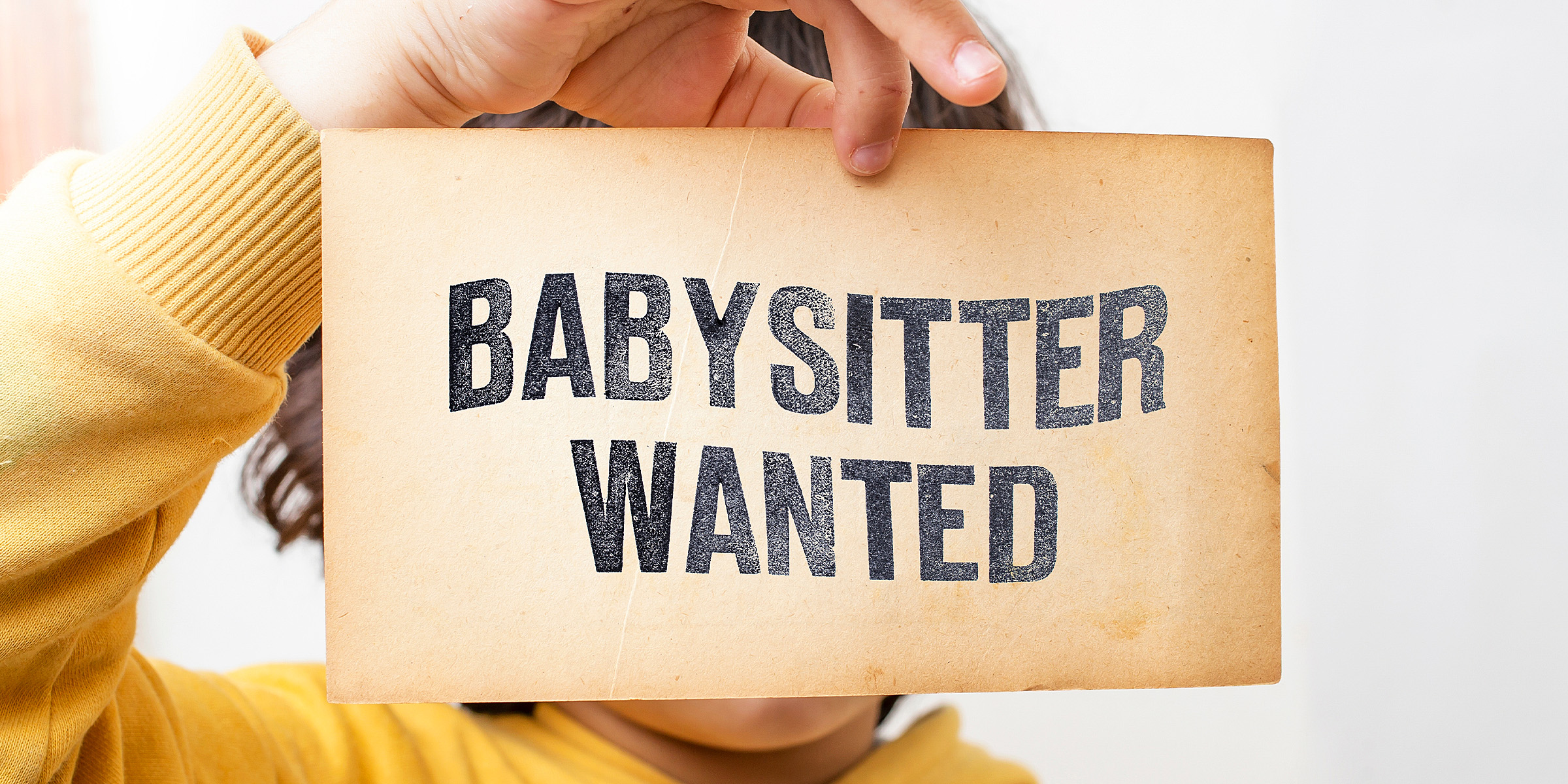 A person holding a flyer with "Babysitter Wanted" written on it | Source: Shutterstock