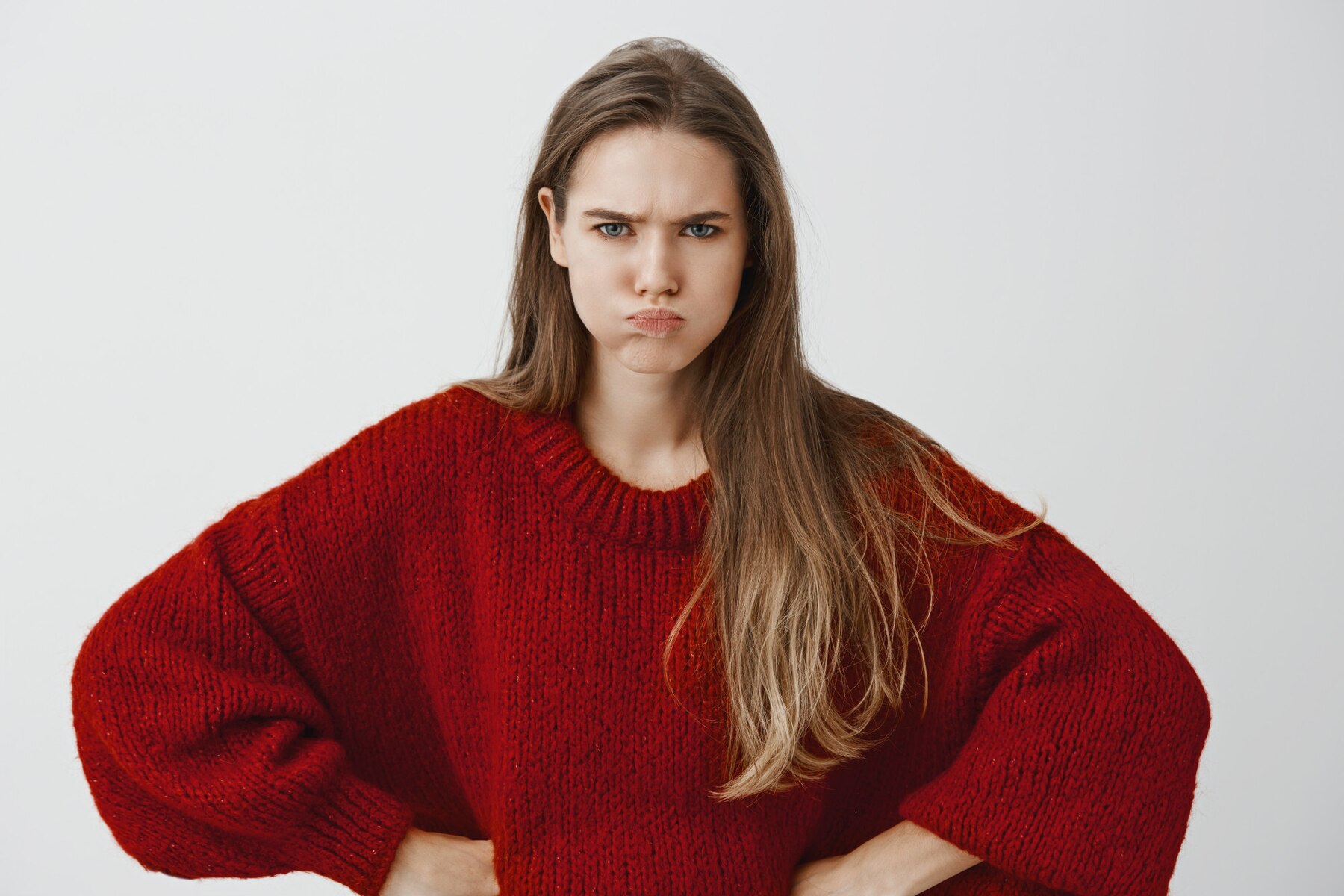 An angry young woman in a red sweater | Source: Freepik